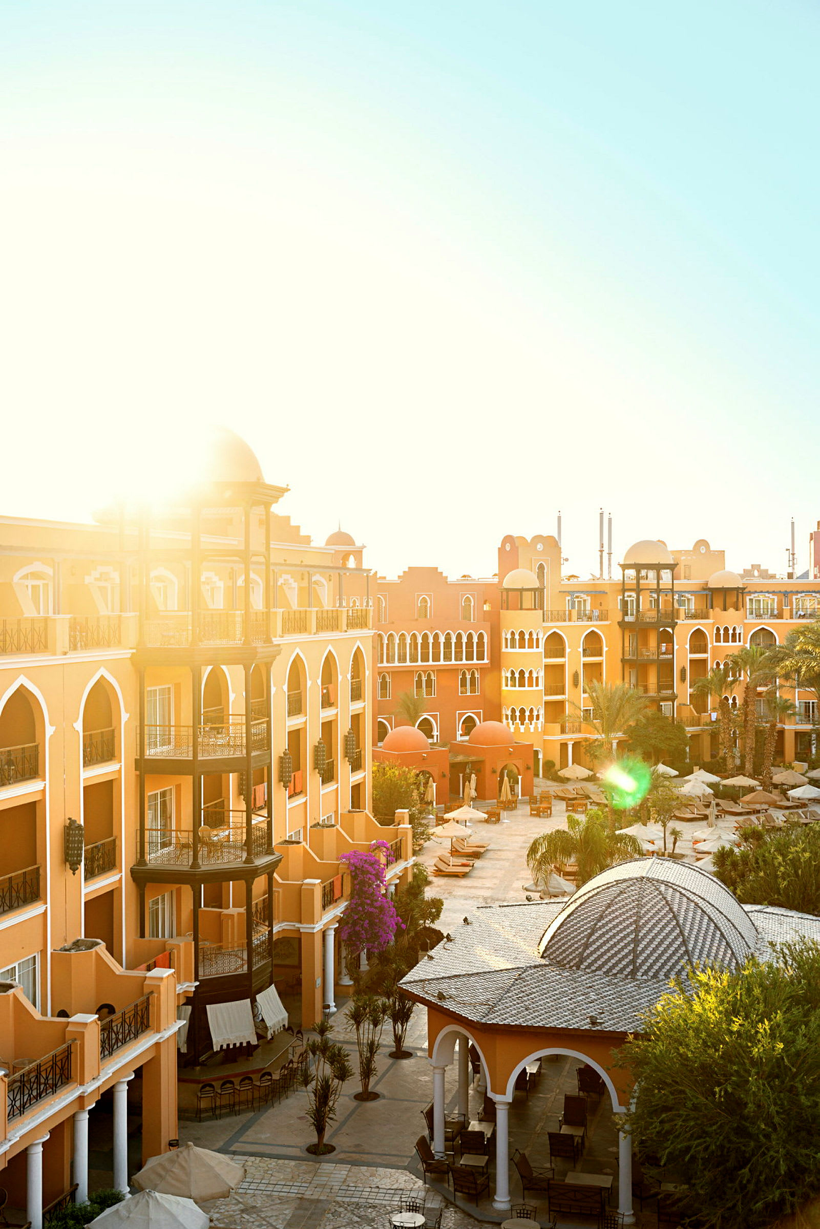 En solbelyst resort med arkitektur i orientalisk stil, omgiven av palmer och sittområden. (AI-genererad text)