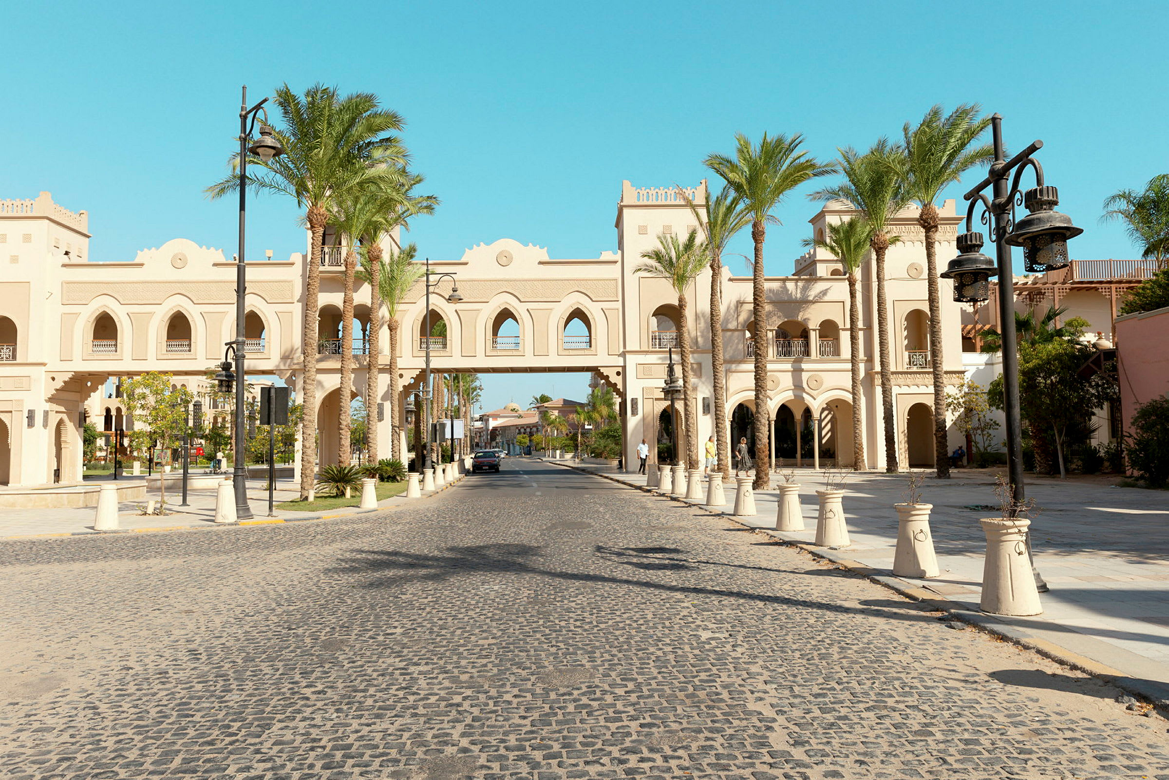 En gatuscen med en ljus byggnad i orientalisk arkitektur och palmer. (AI-genererad text)