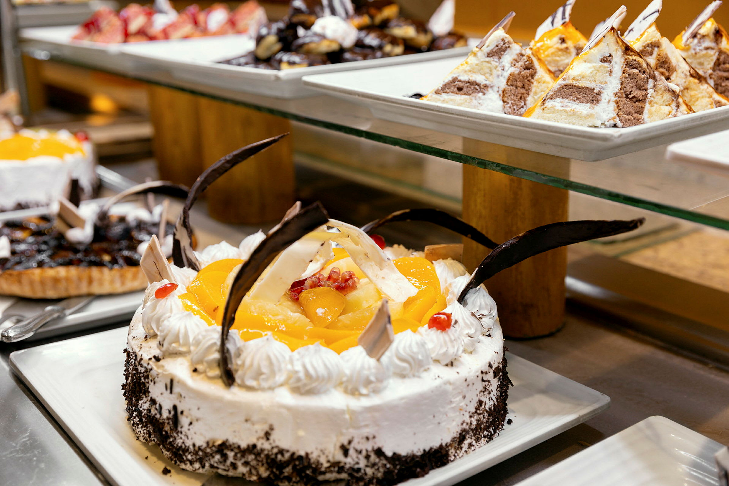 En utsökt buffé av desserter, där en dekorerad tårta med frukt och choklad är framträdande. (AI-genererad text)
