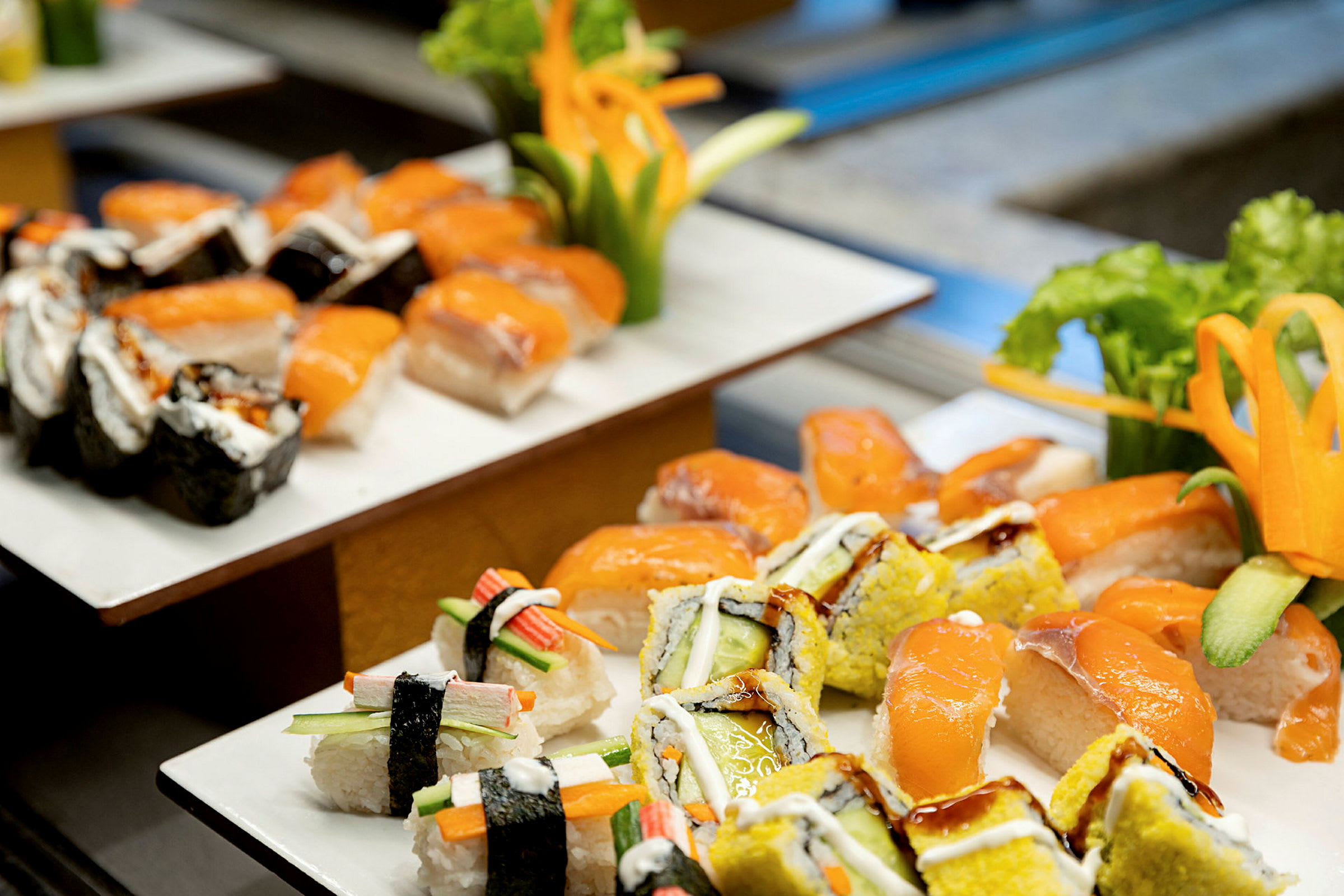 En tallrik med olika sorters sushi, inklusive nigiri med lax och makirullar, dekorerad med färska grönsaker. (AI-genererad text)