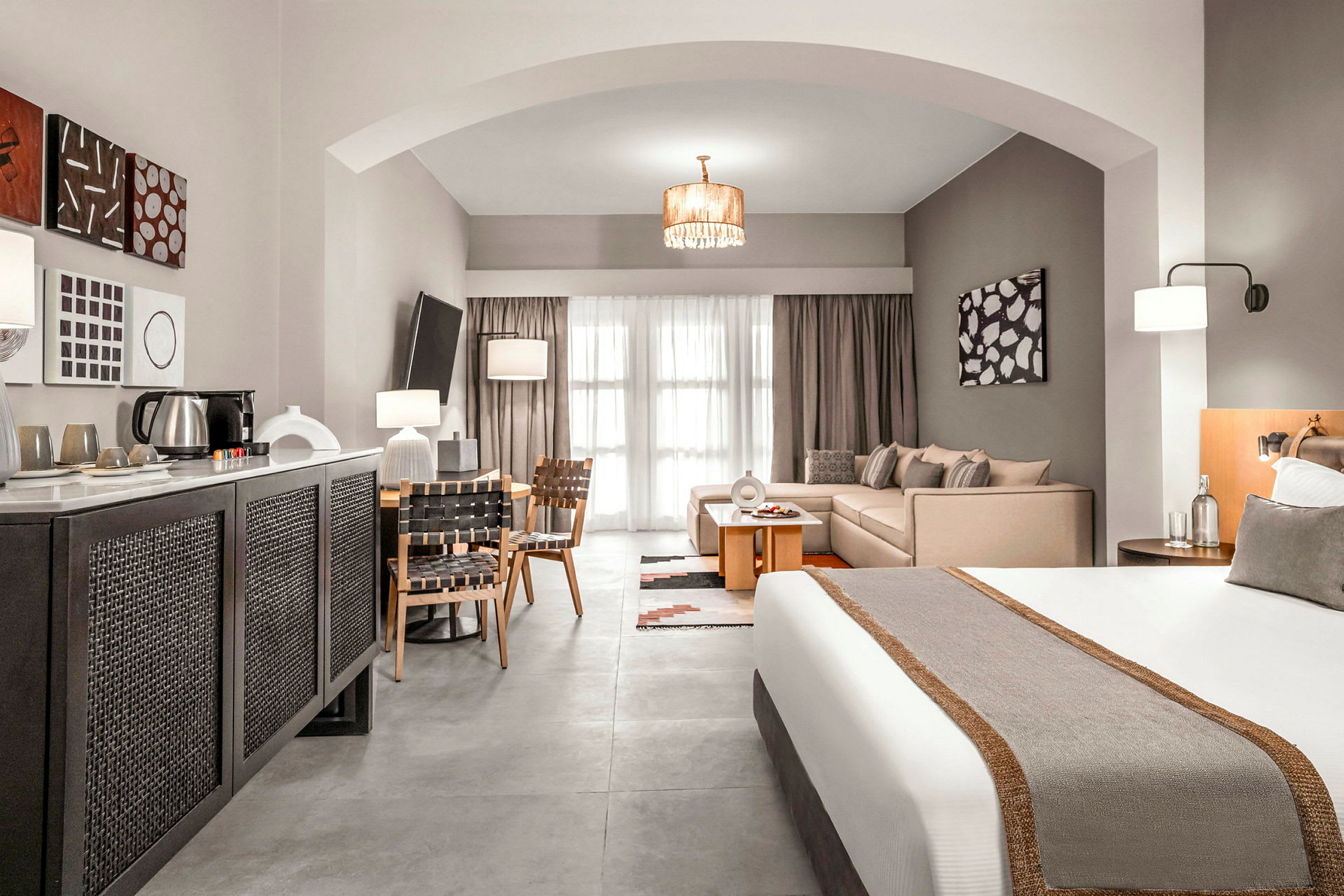 Ett hotellrum med en säng, sittgrupp och matbord, samt modern inredning. (AI-genererad text)