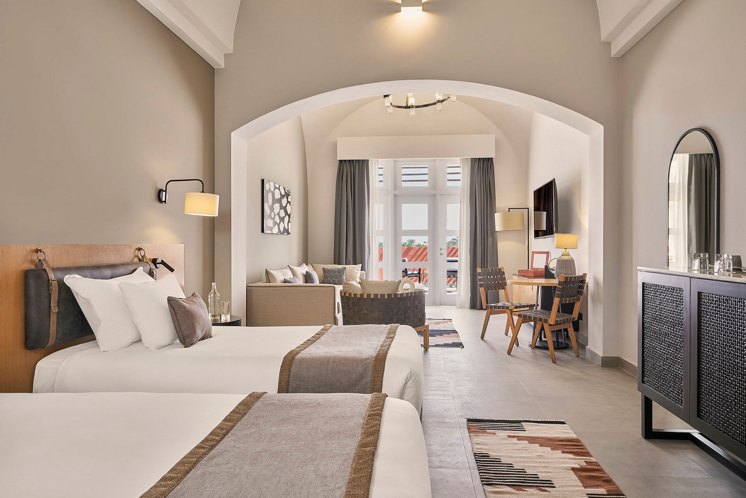 Hotellrum med två enkelsängar, sittgrupp, skrivbord och balkong. (AI-genererad text)