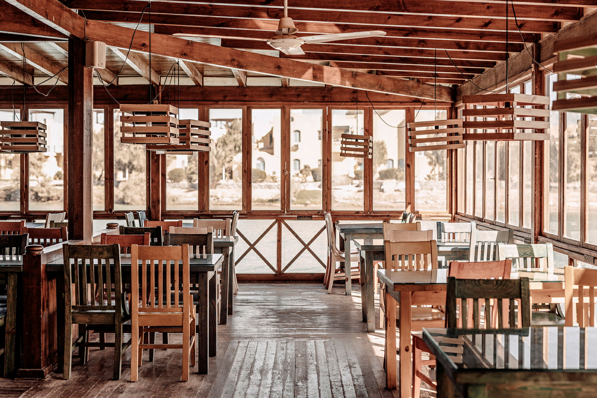 En restaurang med trämöbler och stora fönster. (AI-genererad text)