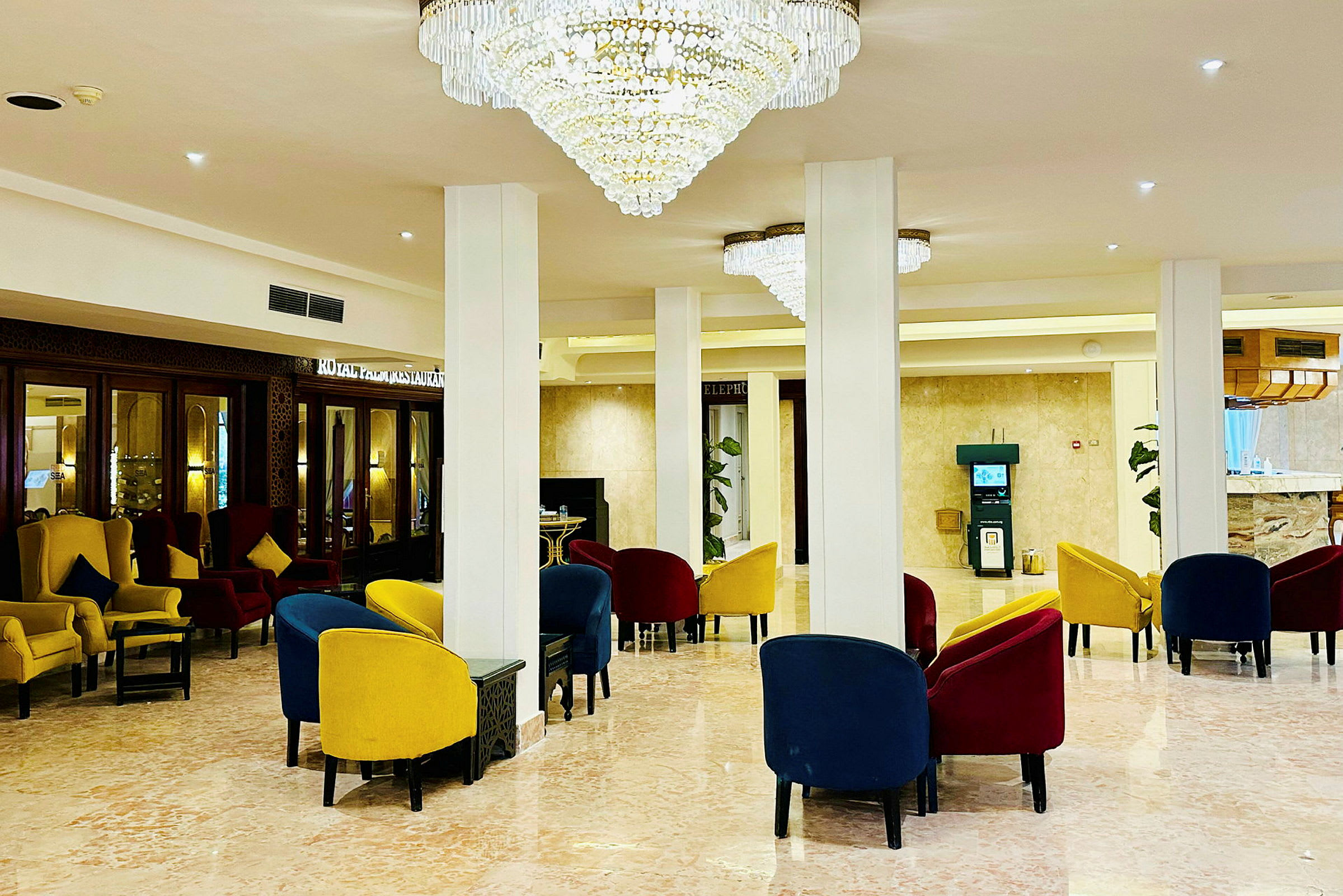 Ett elegant hotellobbyområde med färgglada stolar och ståtliga ljuskronor. (AI-genererad text)