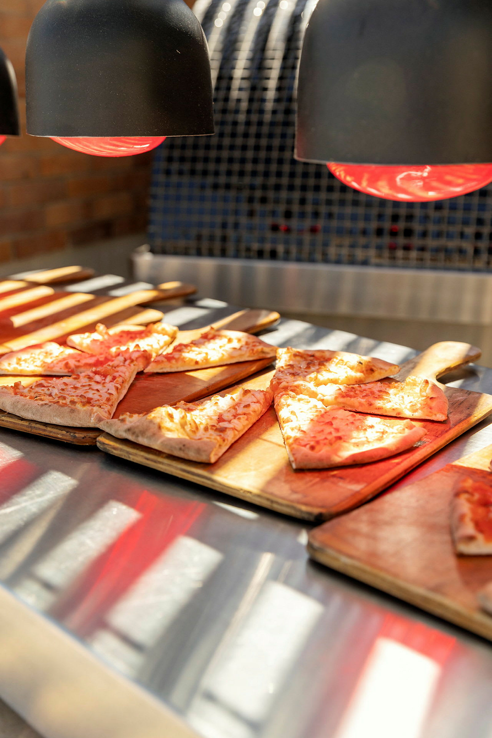 Pizza på skärbrädor under värmelampor. (AI-genererad text)