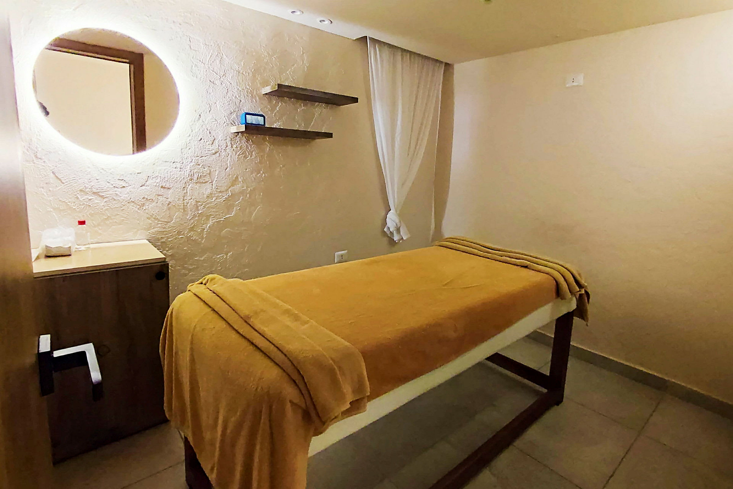 Ett rum med en massagebänk täckt med guldfärgade lakan. (AI-genererad text)