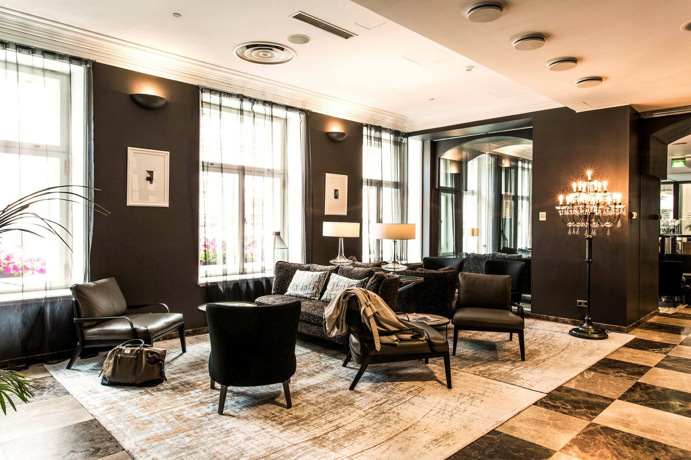 Ett elegant hotellrum med sittmöbler, vägglampor och fönster med ljusa gardiner. (AI-genererad text)
