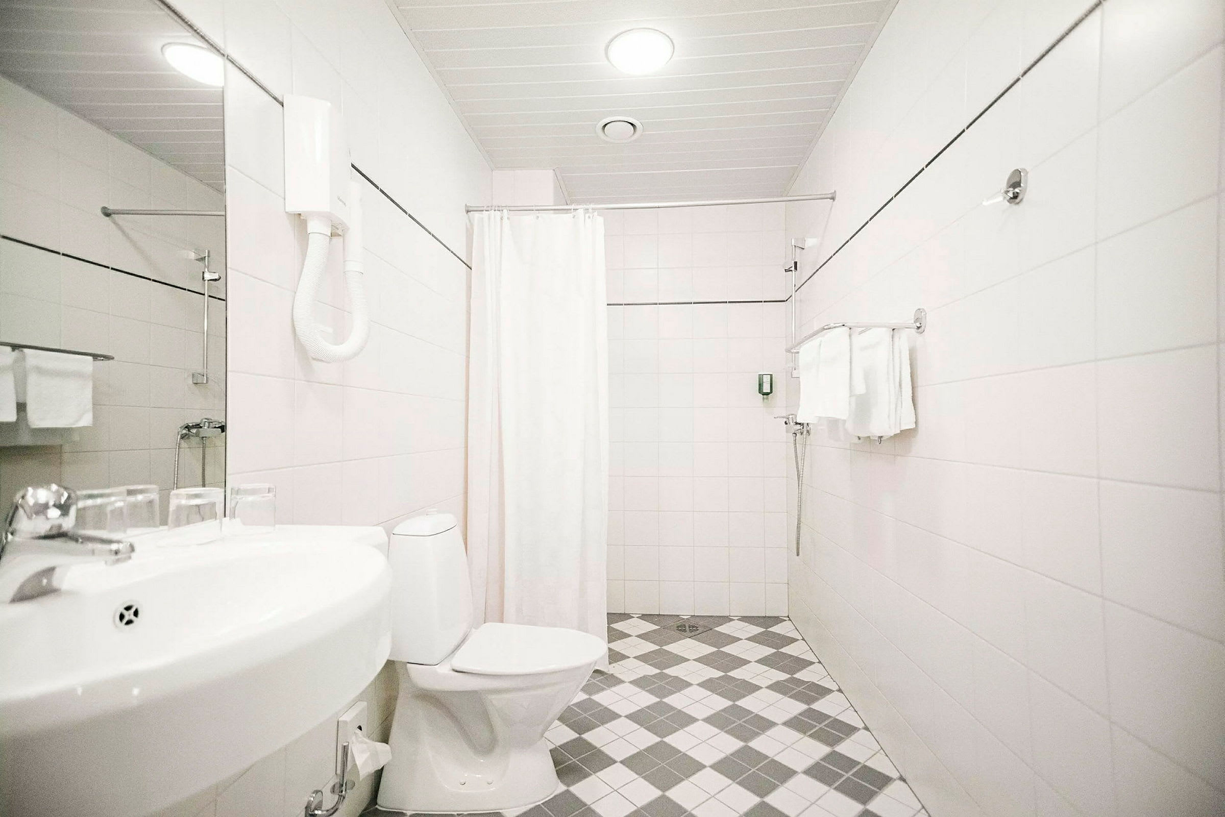 Hotellbadrum med toalett, handfat och dusch. (AI-genererad text)