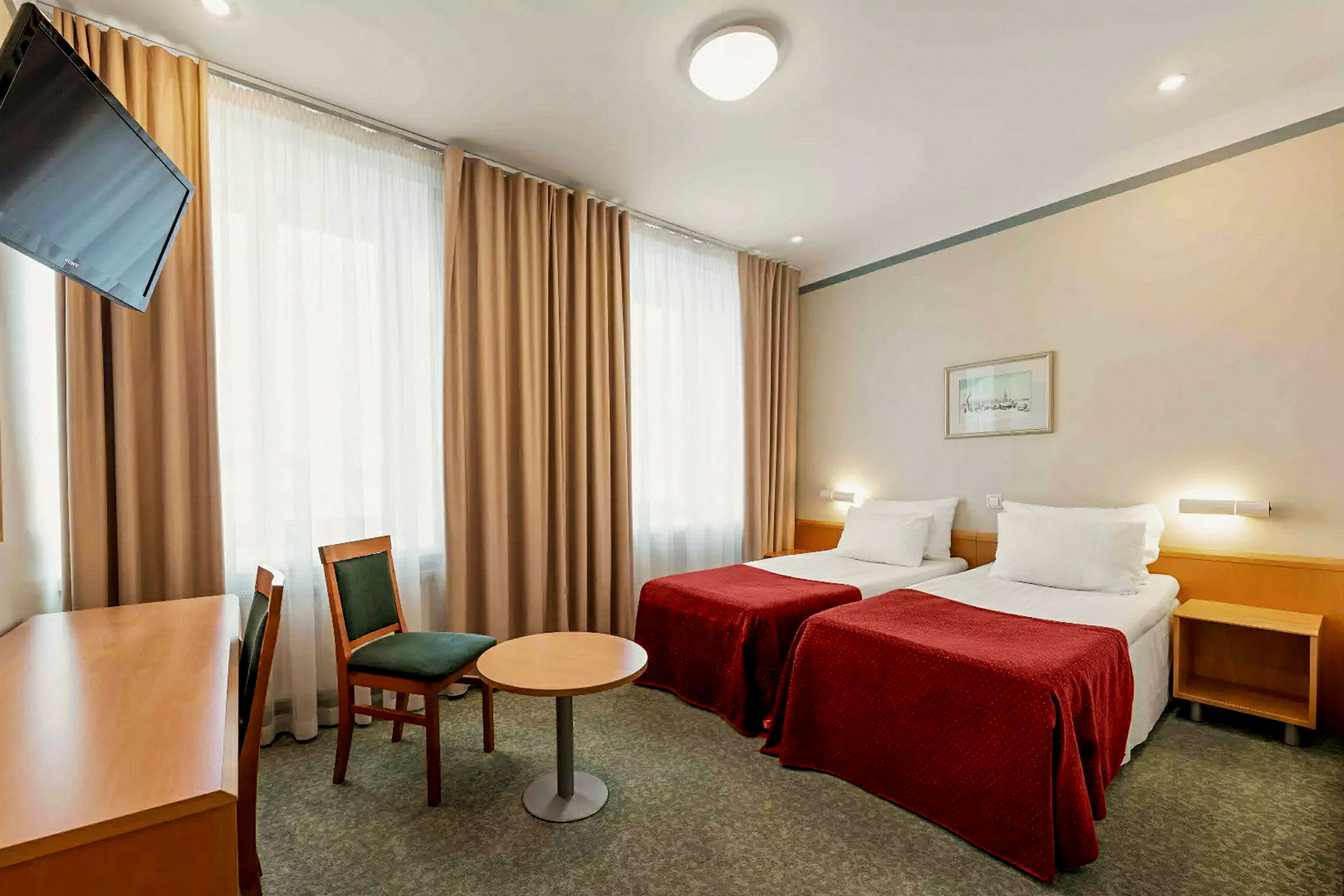 Ett hotellrum med två enkelsängar, en stol, ett bord och en skrivbord med en TV framför. (AI-genererad text)