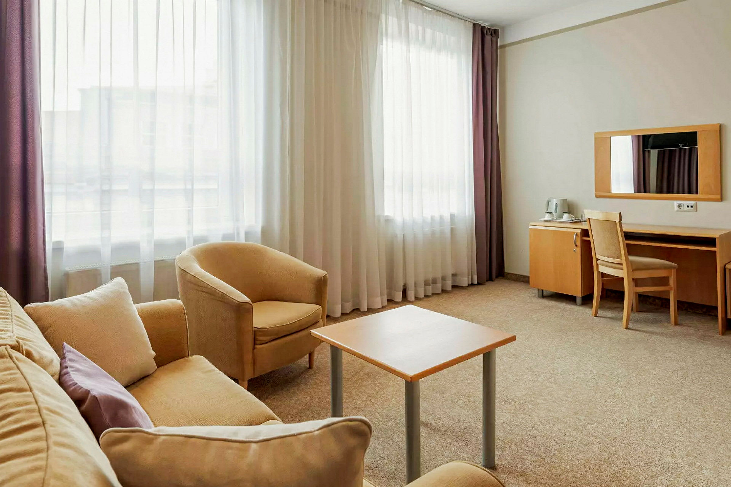 Ett hotellrum med sittgrupp och skrivbord. (AI-genererad text)