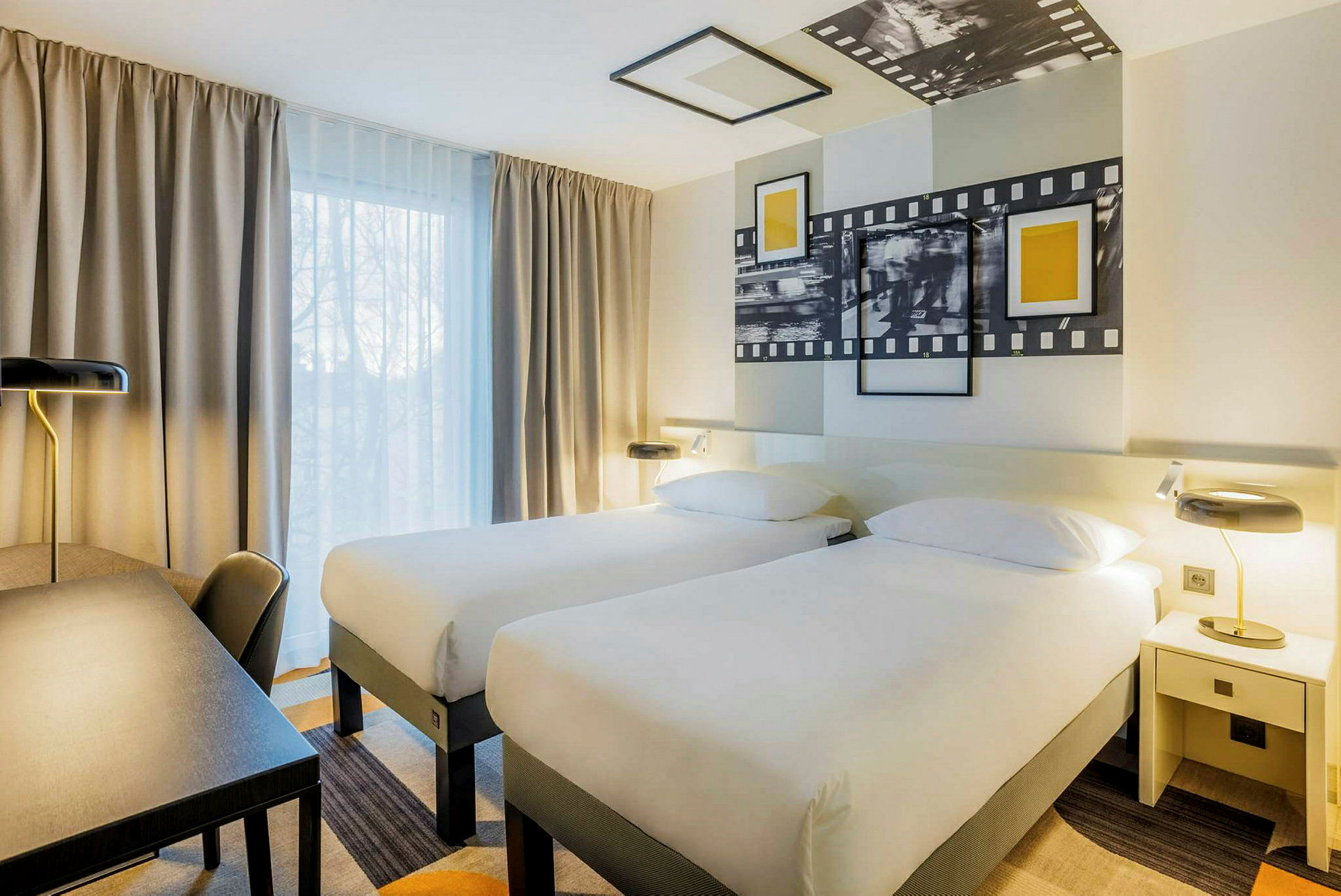 Bild av ett hotellrum med två enkelsängar, ett skrivbord och lampor. (AI-genererad text)
