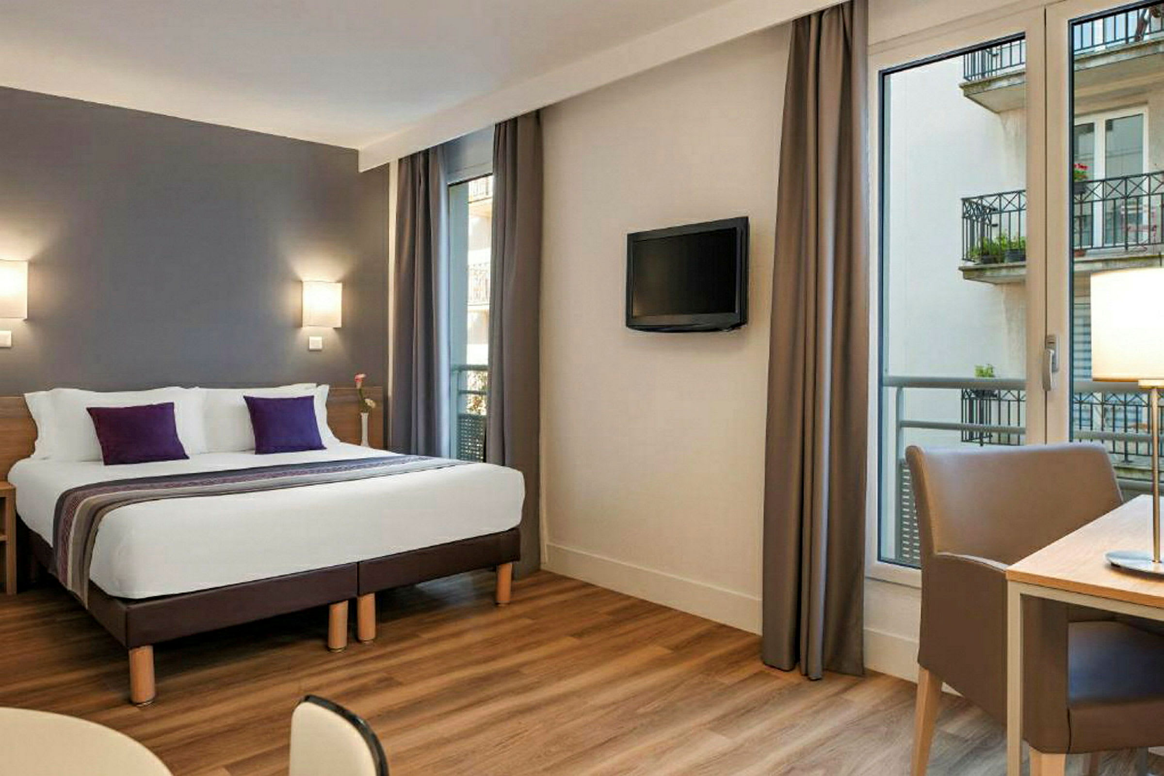 Ett hotellrum med en dubbelsäng, skrivbord och en TV på väggen. (AI-genererad text)