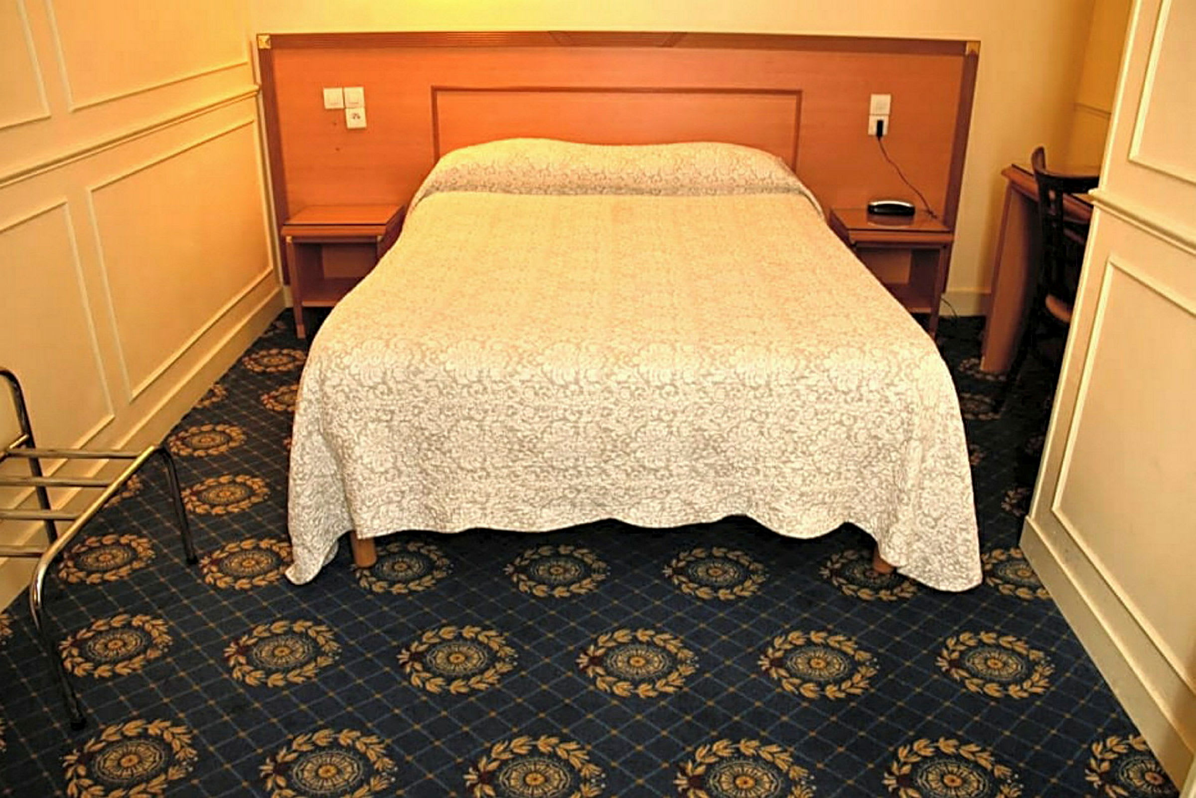 Ett hotellrum med en dubbelsäng, mörkblå matta och ett vitt överkast. (AI-genererad text)