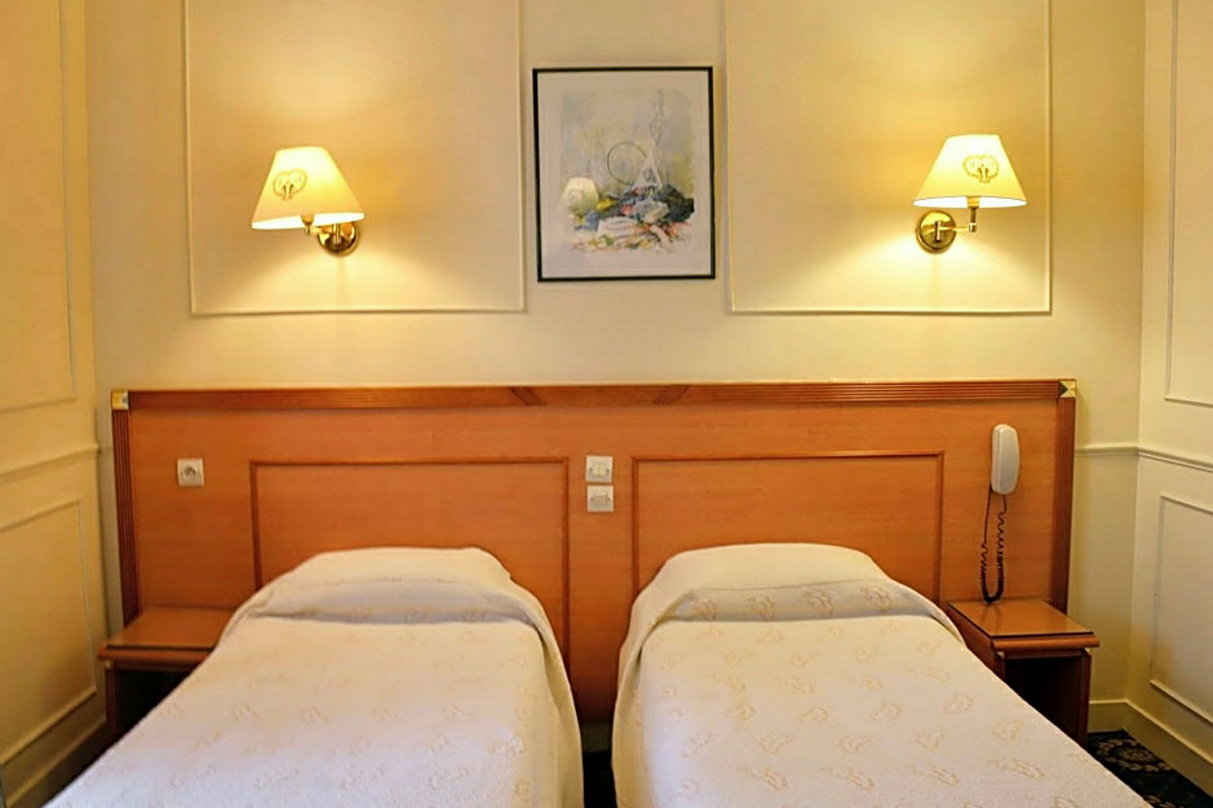 Ett hotellrum med två enkelsängar och sänglampor på väggen. (AI-genererad text)