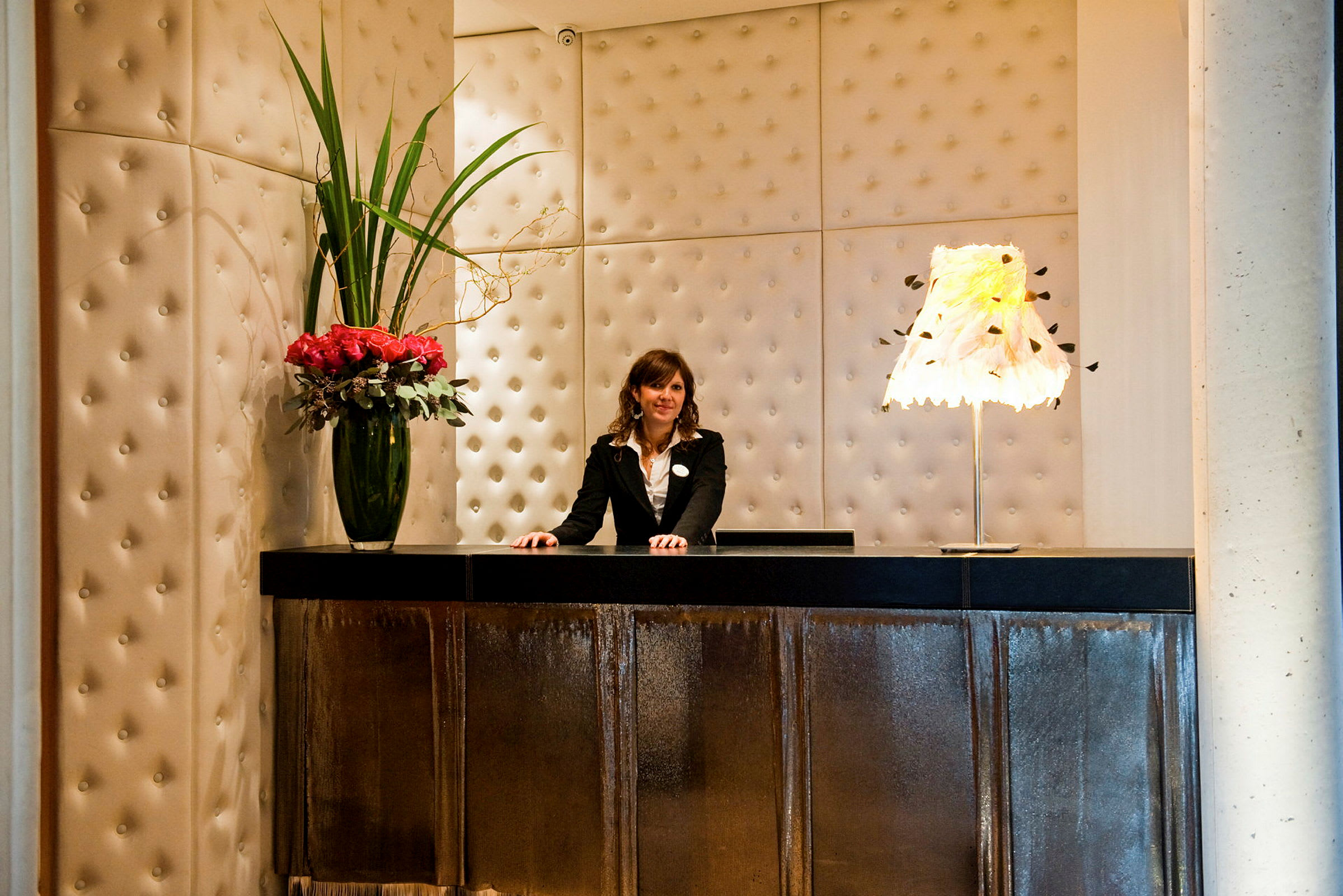 En reception med en stilren inredning inklusive en vas med blommor och en dekorativ bordslampa. (AI-genererad text)