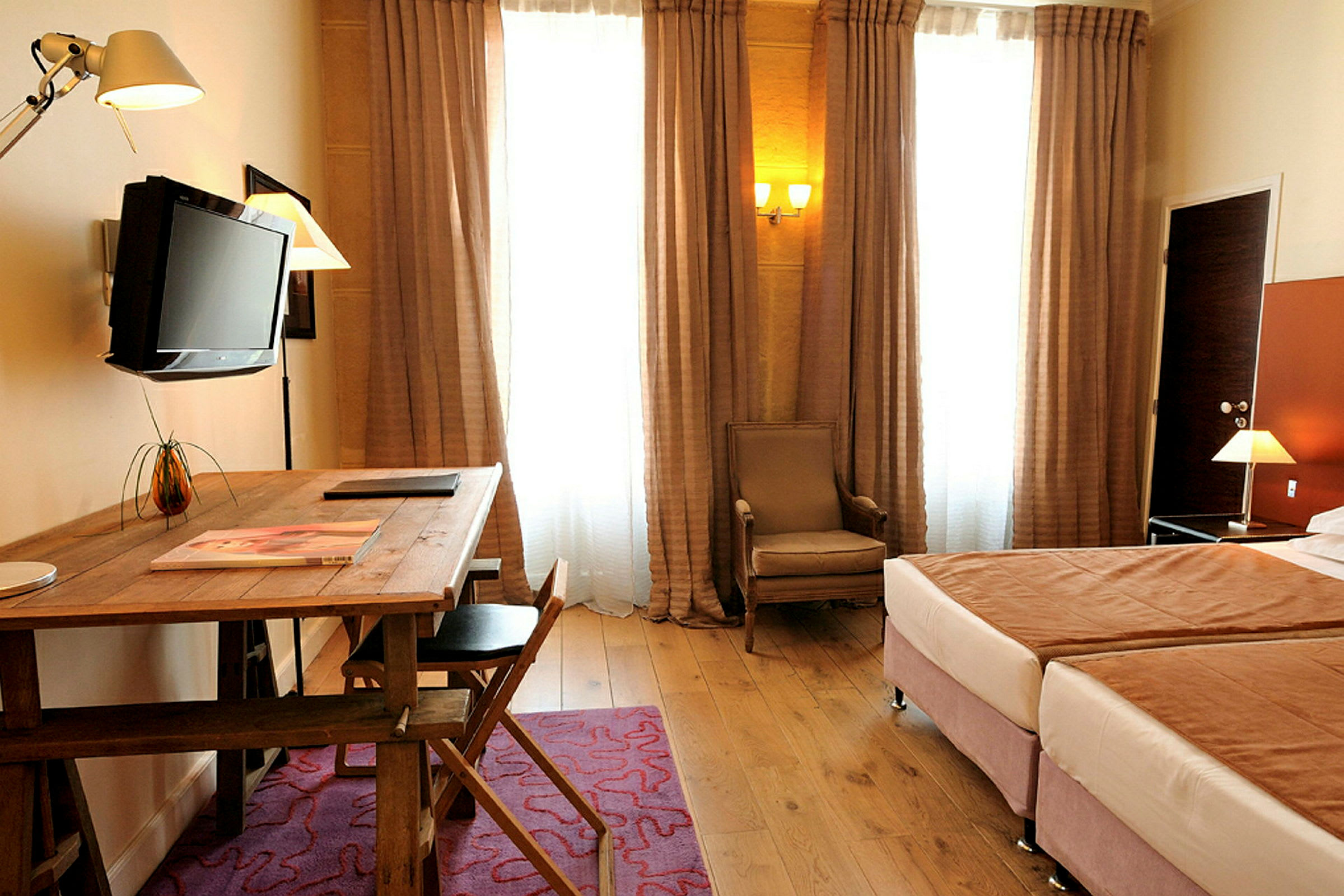 Ett hotellrum med två sängar, skrivbord med stol, och TV. (AI-genererad text)