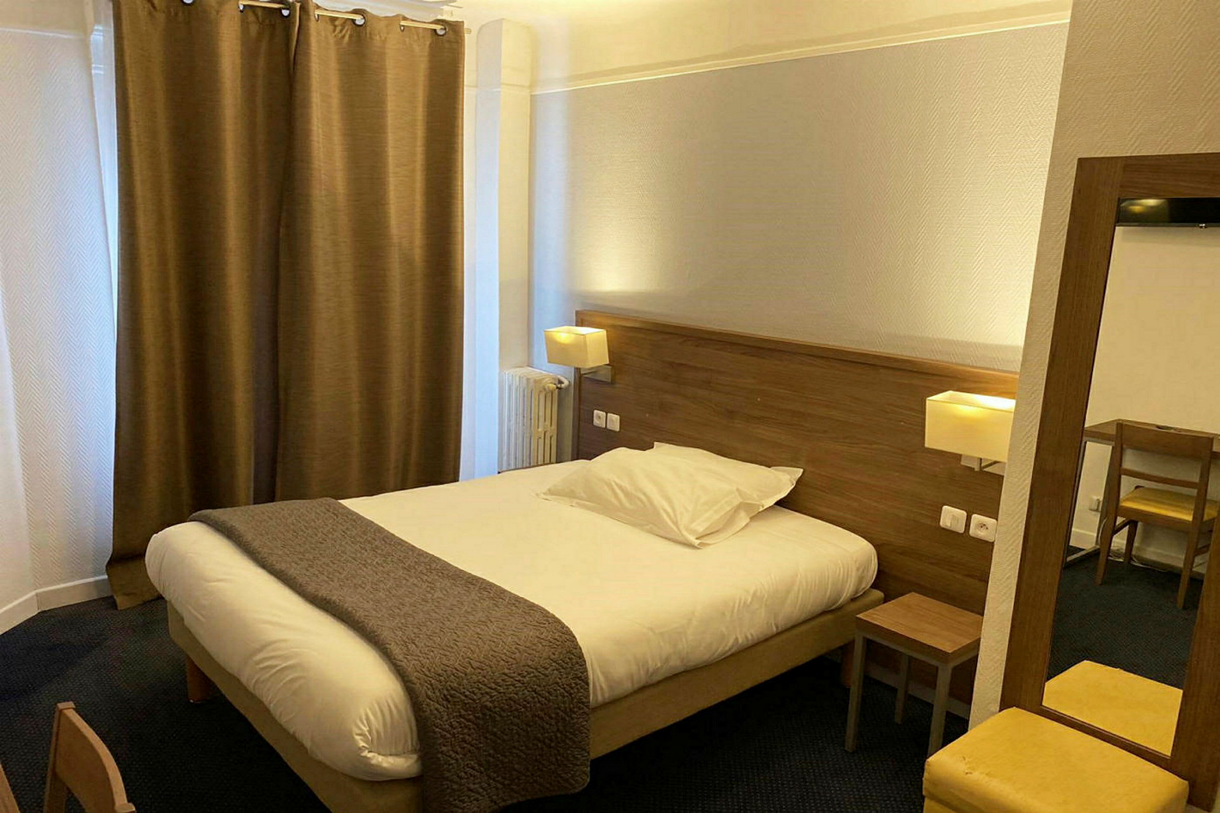 Hotelrum med en dubbelsäng, nattbord och skrivbord. (AI-genererad text)