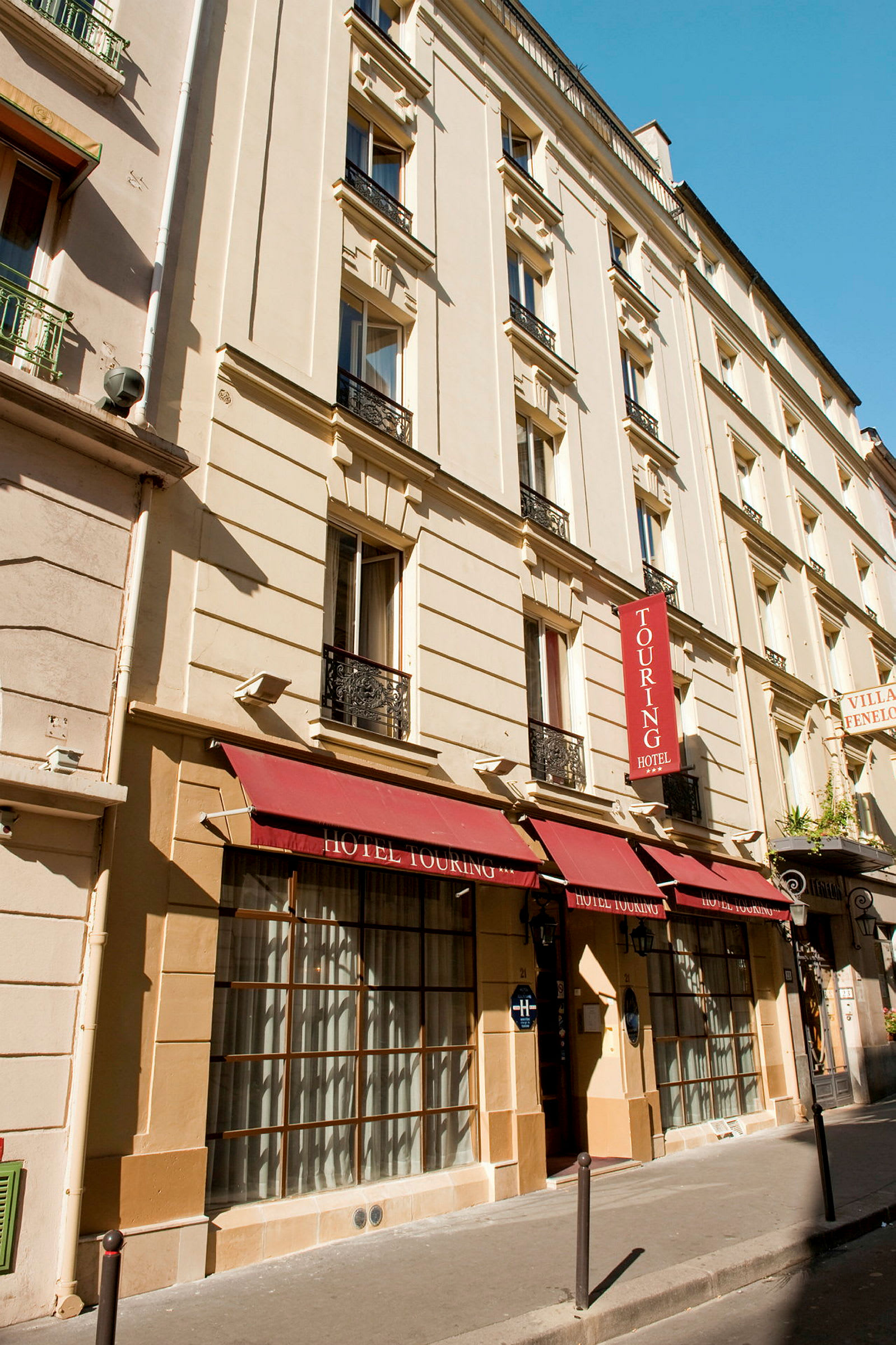 Fasad av hotellbyggnad med röd markis och skyltar. (AI-genererad text)
