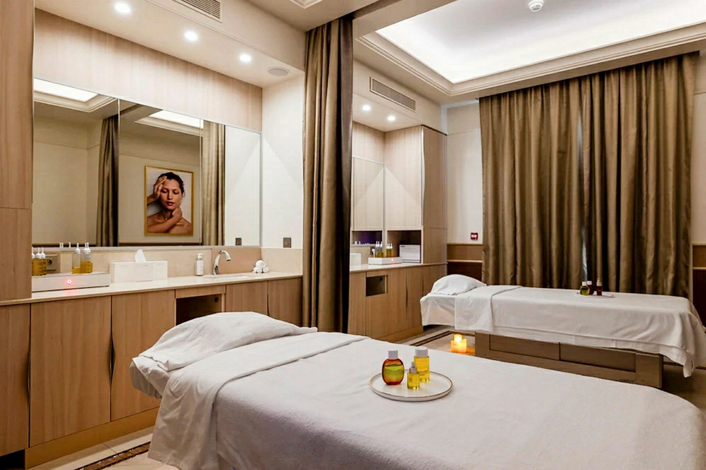 Rum med två massagebänkar och en spegel över diskbänk. (AI-genererad text)