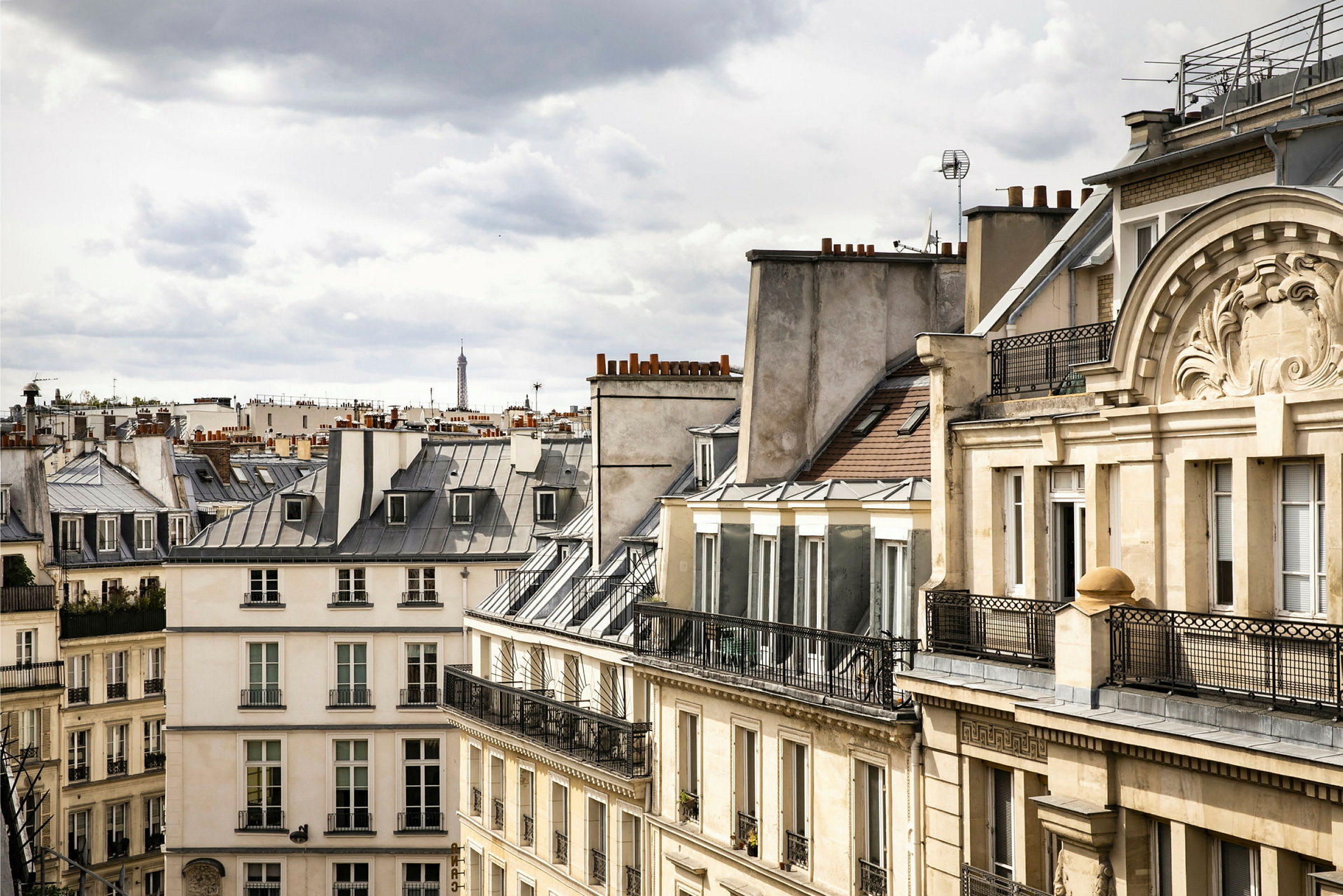 Bild på parisiska byggnader med typiska tak, med Eiffeltornet synligt i bakgrunden. (AI-genererad text)