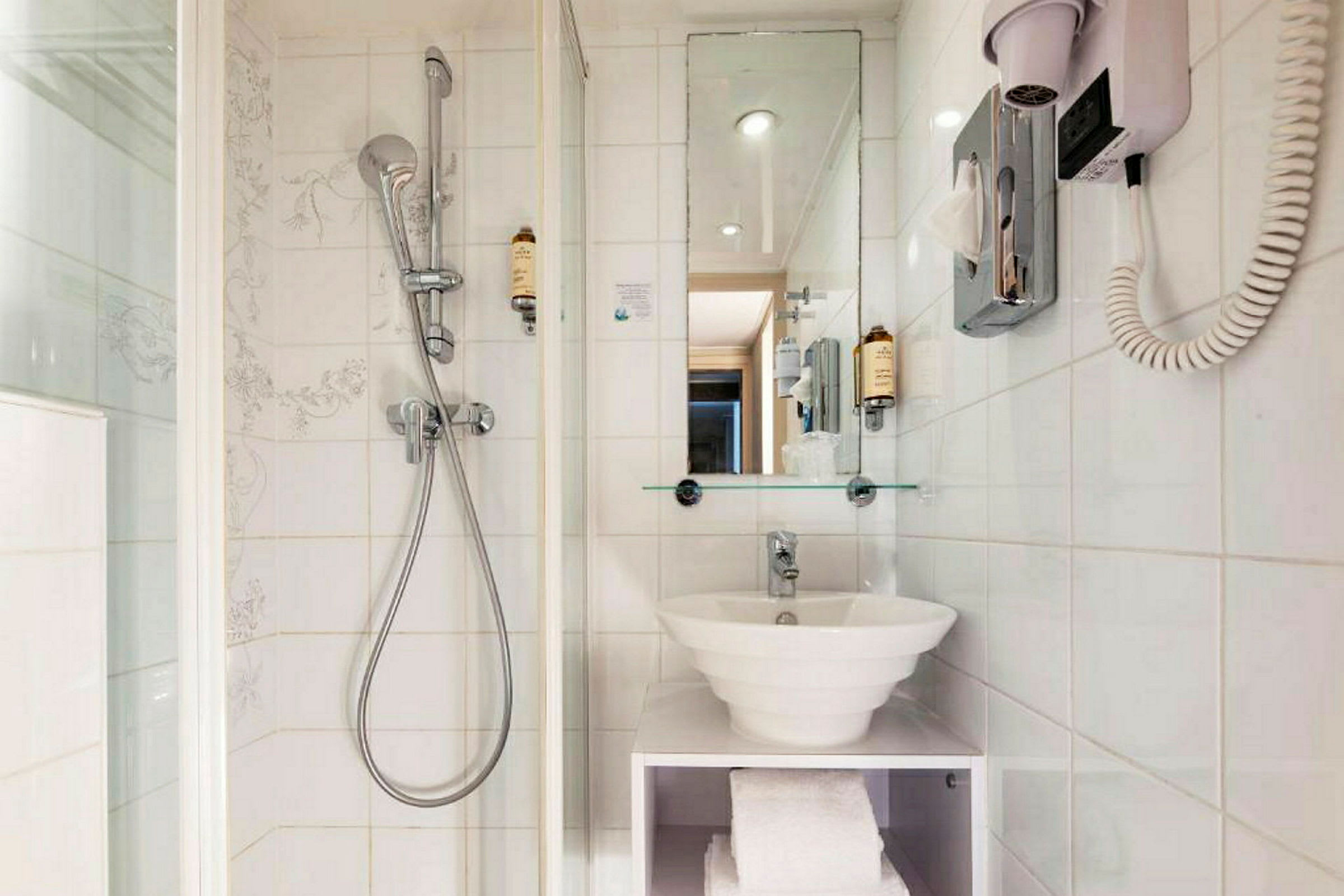 Hotellbad med dusch, spegel och handfat. (AI-genererad text)