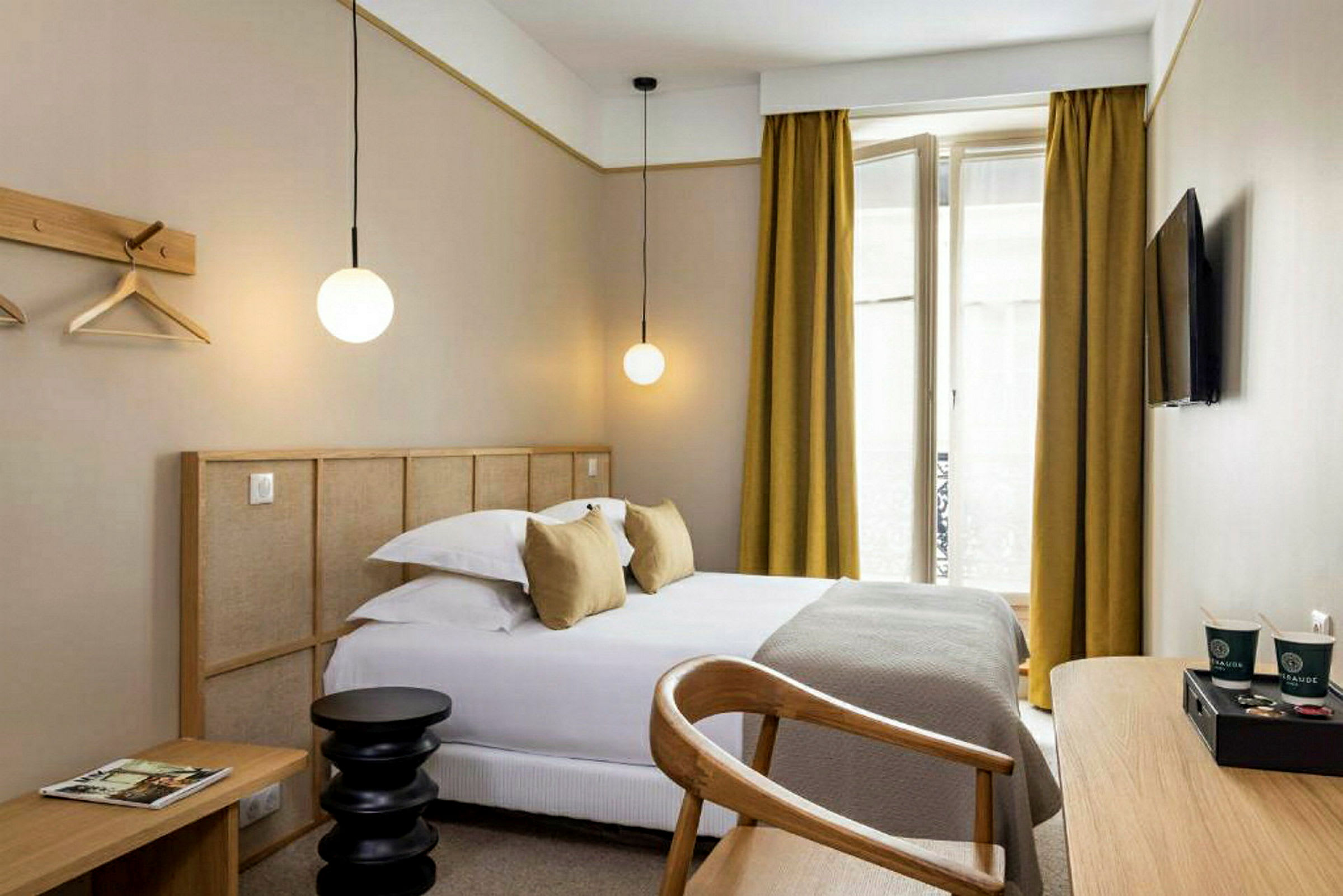 En modern hotellrum med en säng, skrivbord och en TV på väggen. (AI-genererad text)