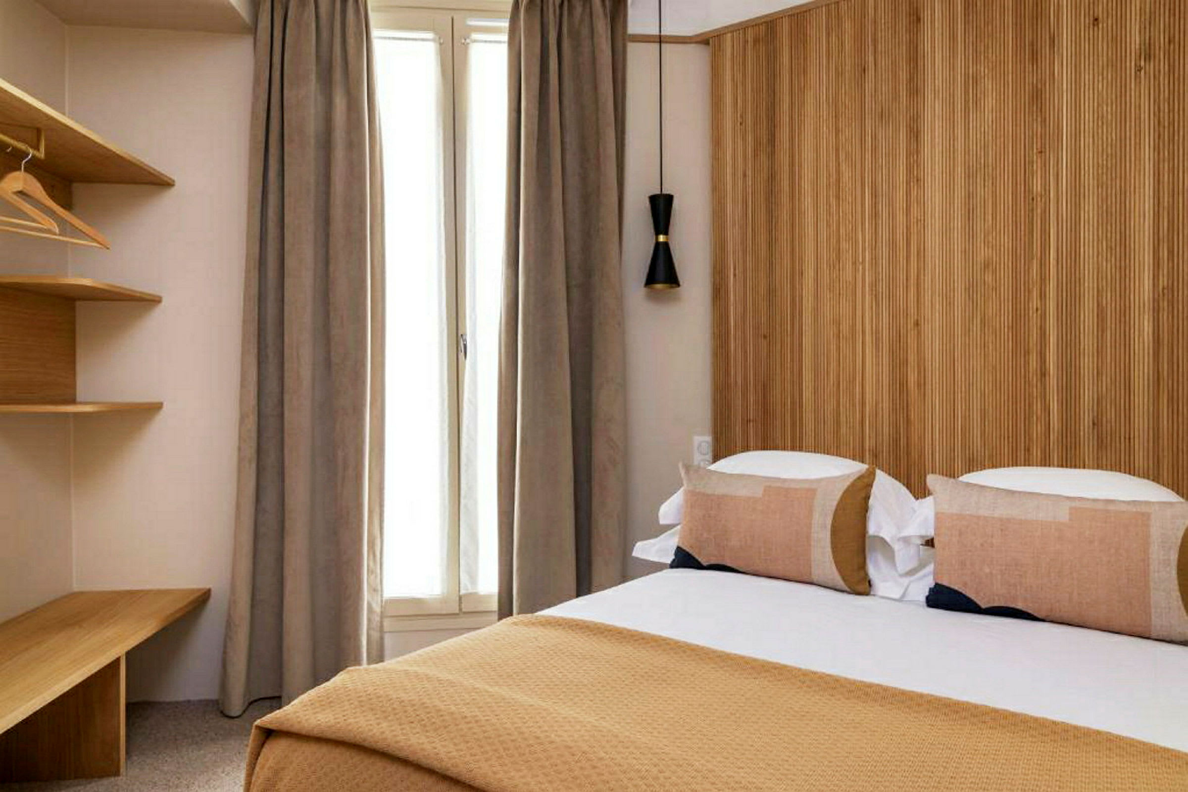 Ett hotellrum med en säng, en träpanelvägg och ett fönster med gardiner. (AI-genererad text)