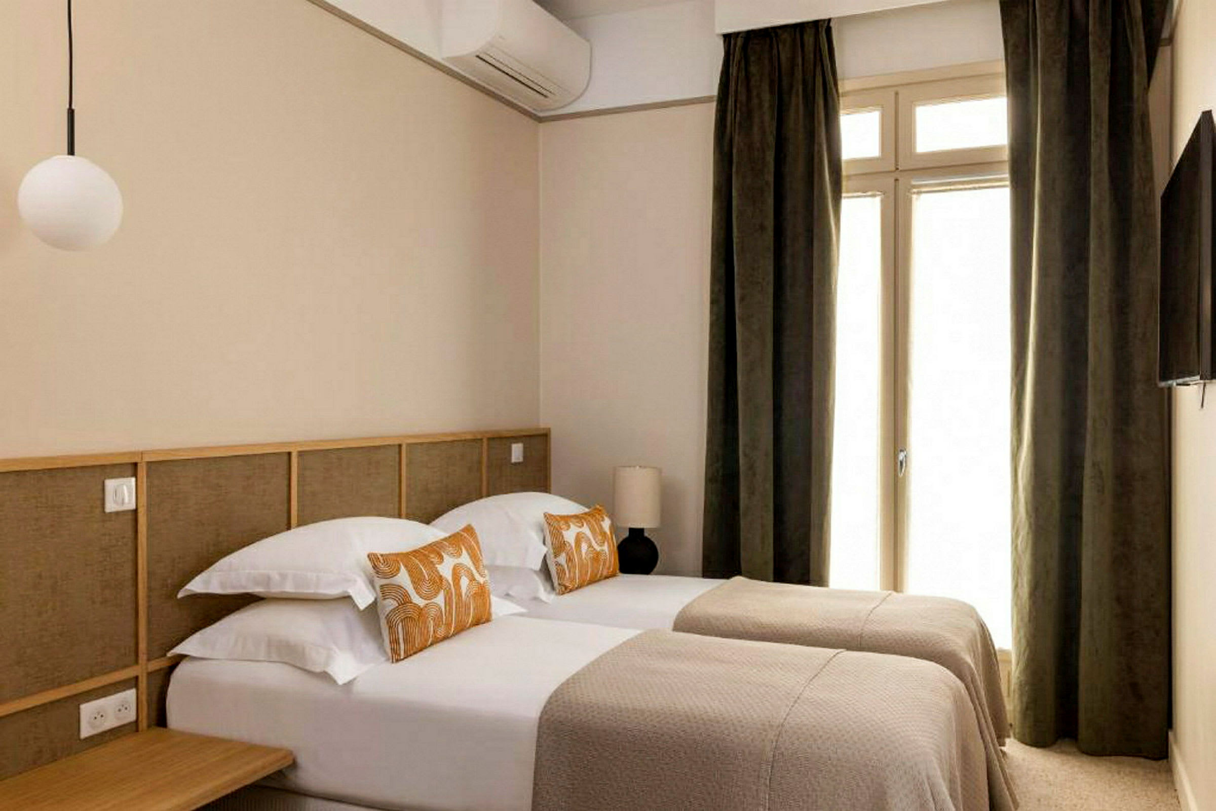 Bild av ett hotellrum med två enkelsängar och en dörr med gardiner. (AI-genererad text)