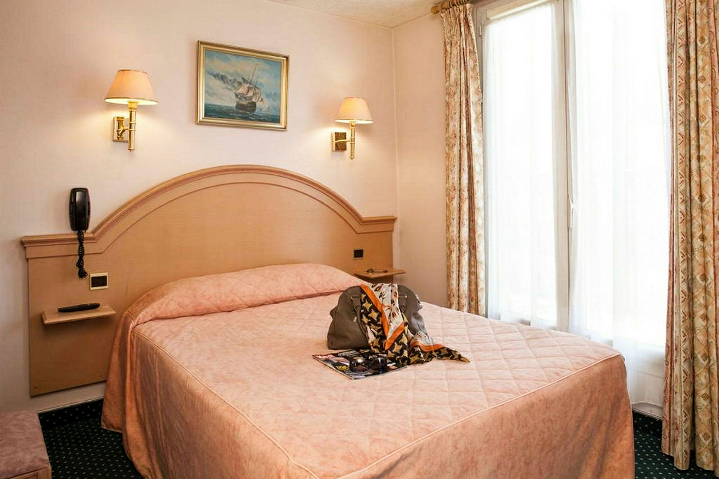 Hotellrum med en dubbelsäng, beige inredning och gardiner samt en tavla på väggen. (AI-genererad text)