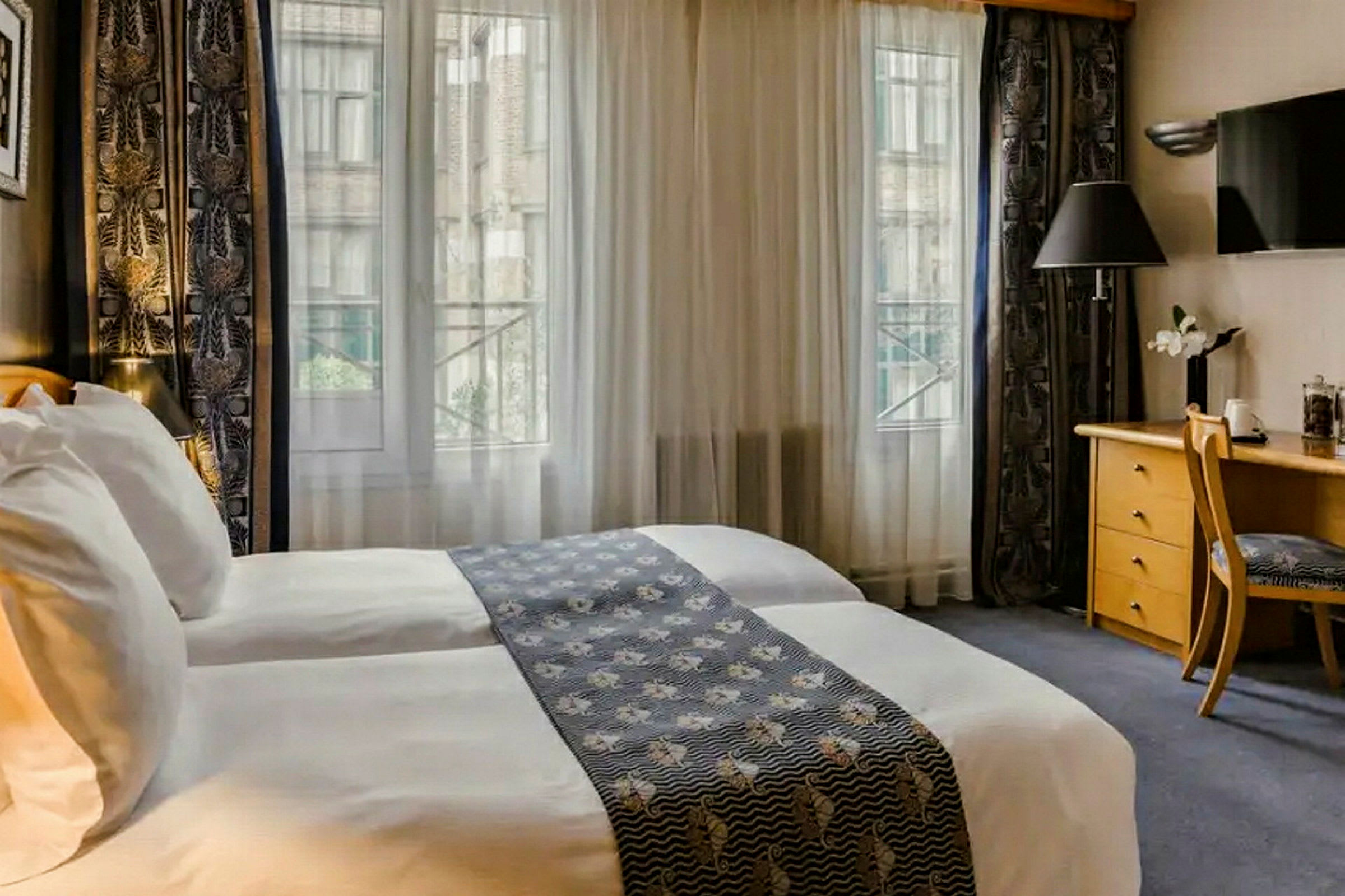 Hotellrum med två sängar, skrivbord och fönster med utsikt. (AI-genererad text)