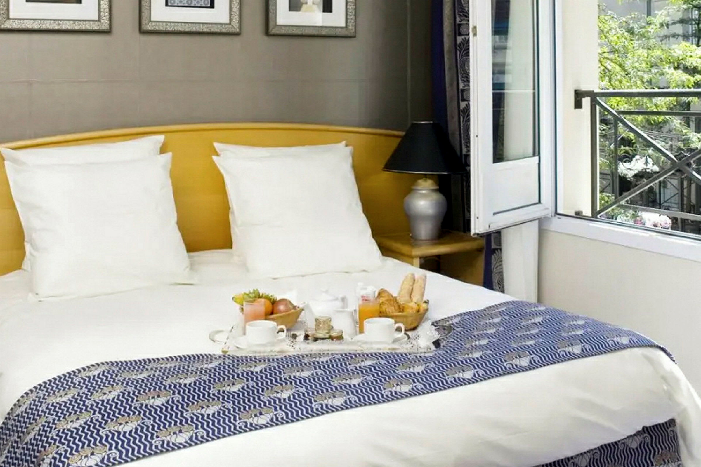 Ett hotellrum med en dubbelsäng, upplagt frukost och en öppen balkongdörr. (AI-genererad text)