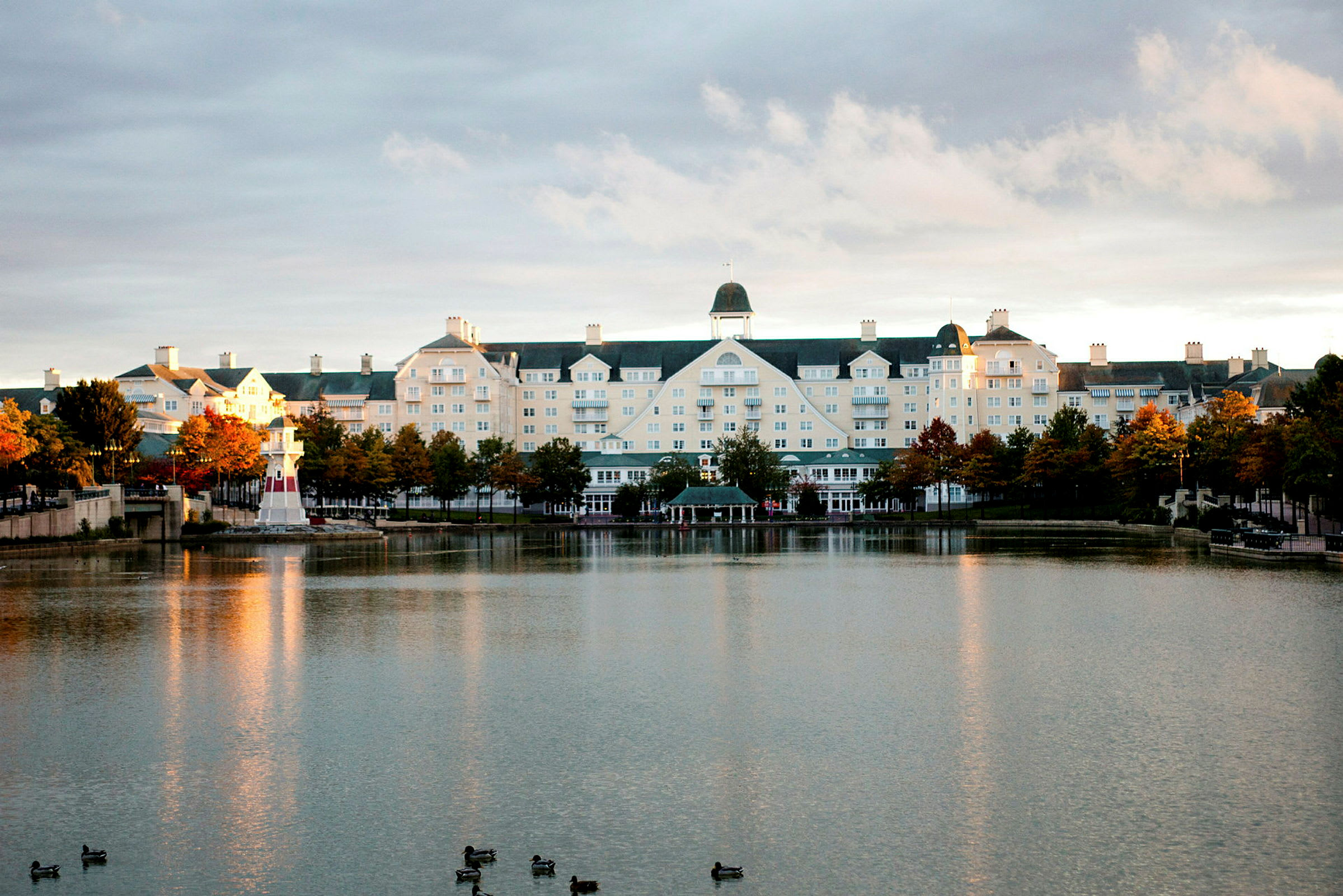 Hotellbyggnad vid en sjö med en liten fyr. (AI-genererad text)
