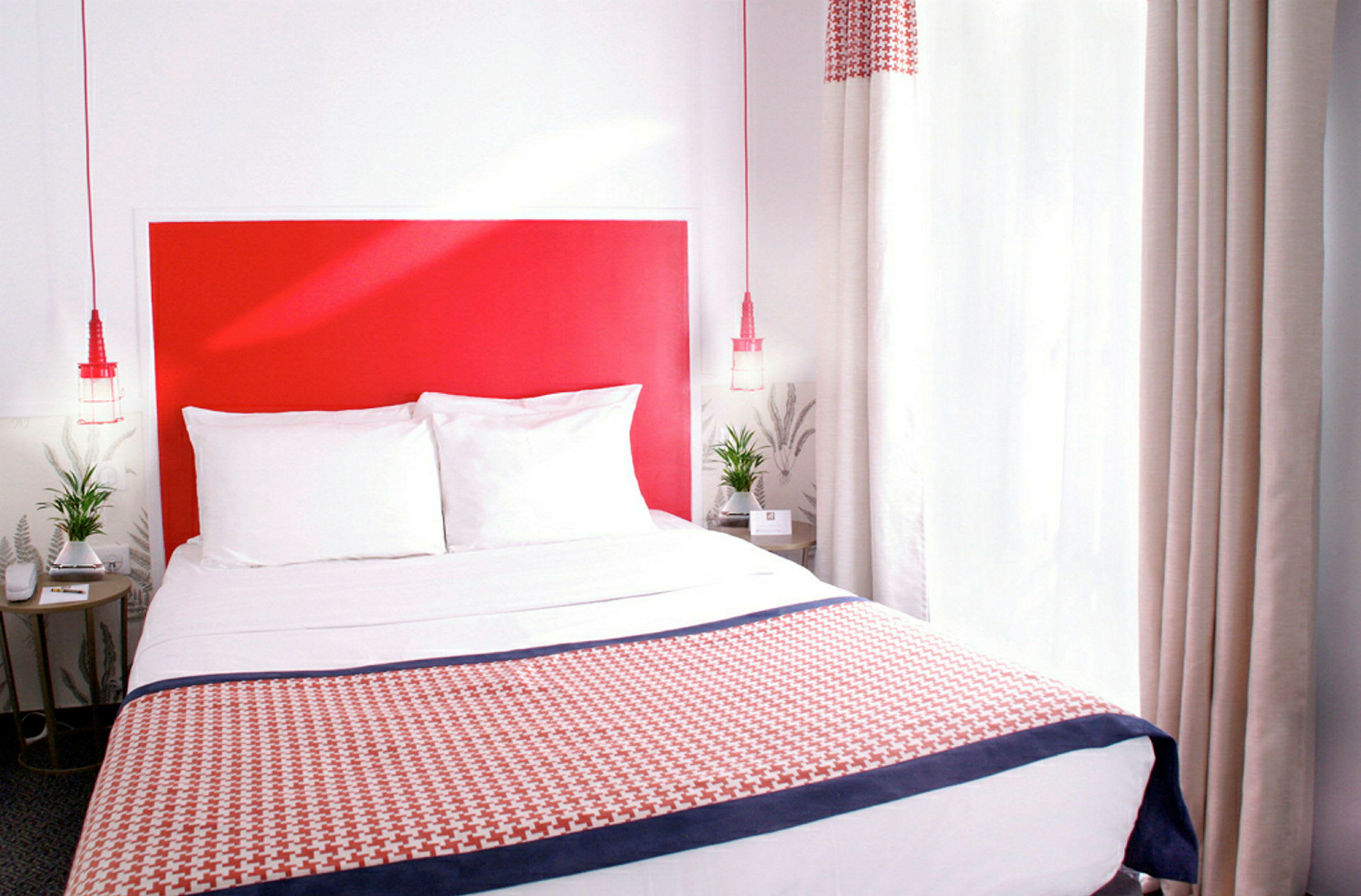 Ett hotellrum med en säng och en röd sänggavel. (AI-genererad text)
