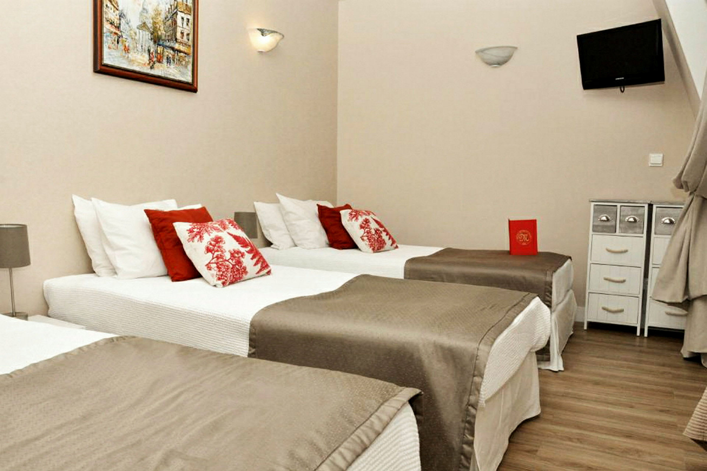 Hotellrum med tre enkelsängar, dekorerade med röda och vita kuddar. (AI-genererad text)