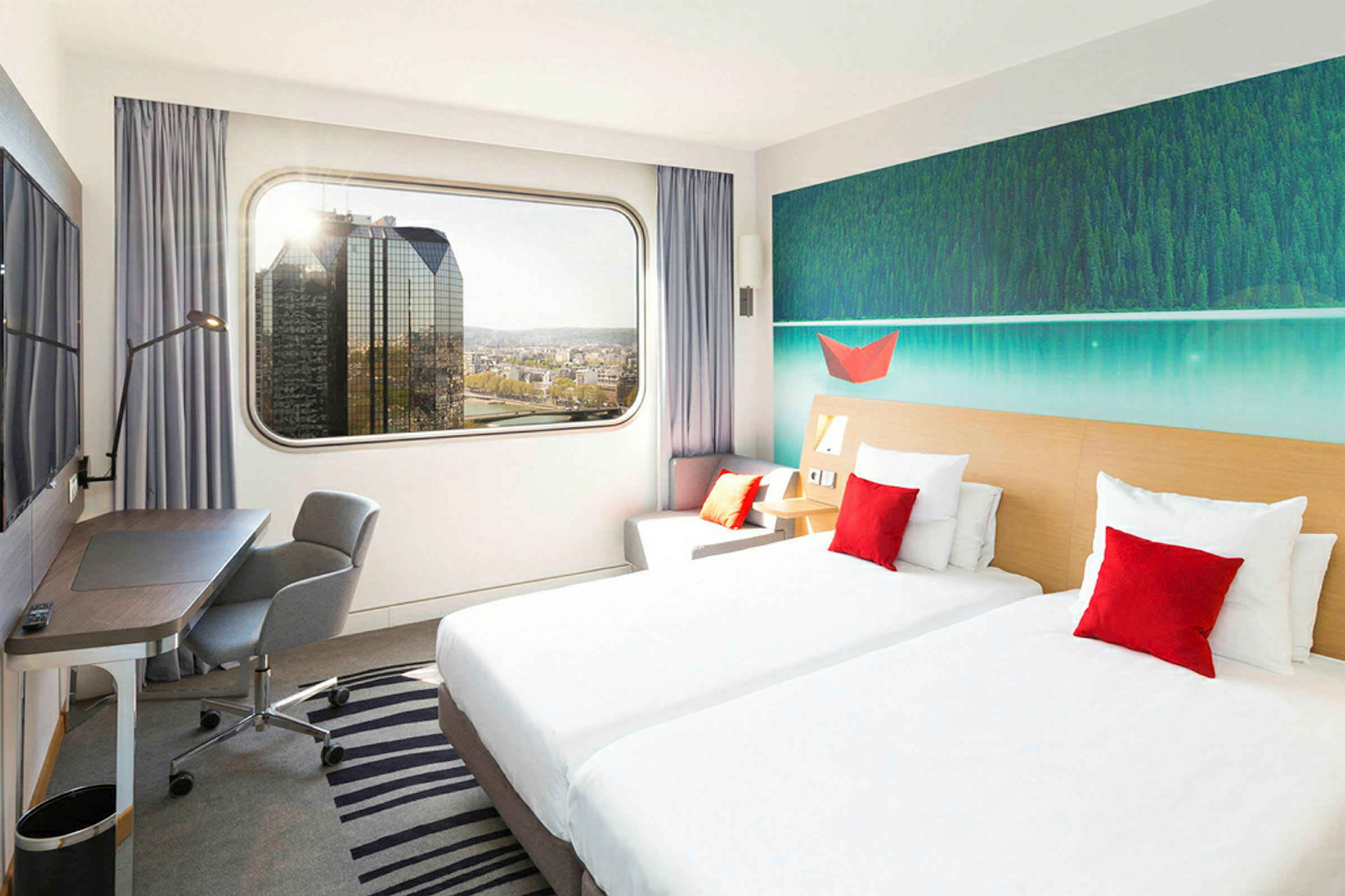 Ett hotellrum med två enkelsängar, en arbetshörna och en stor fönstervy över stadens skyline. (AI-genererad text)