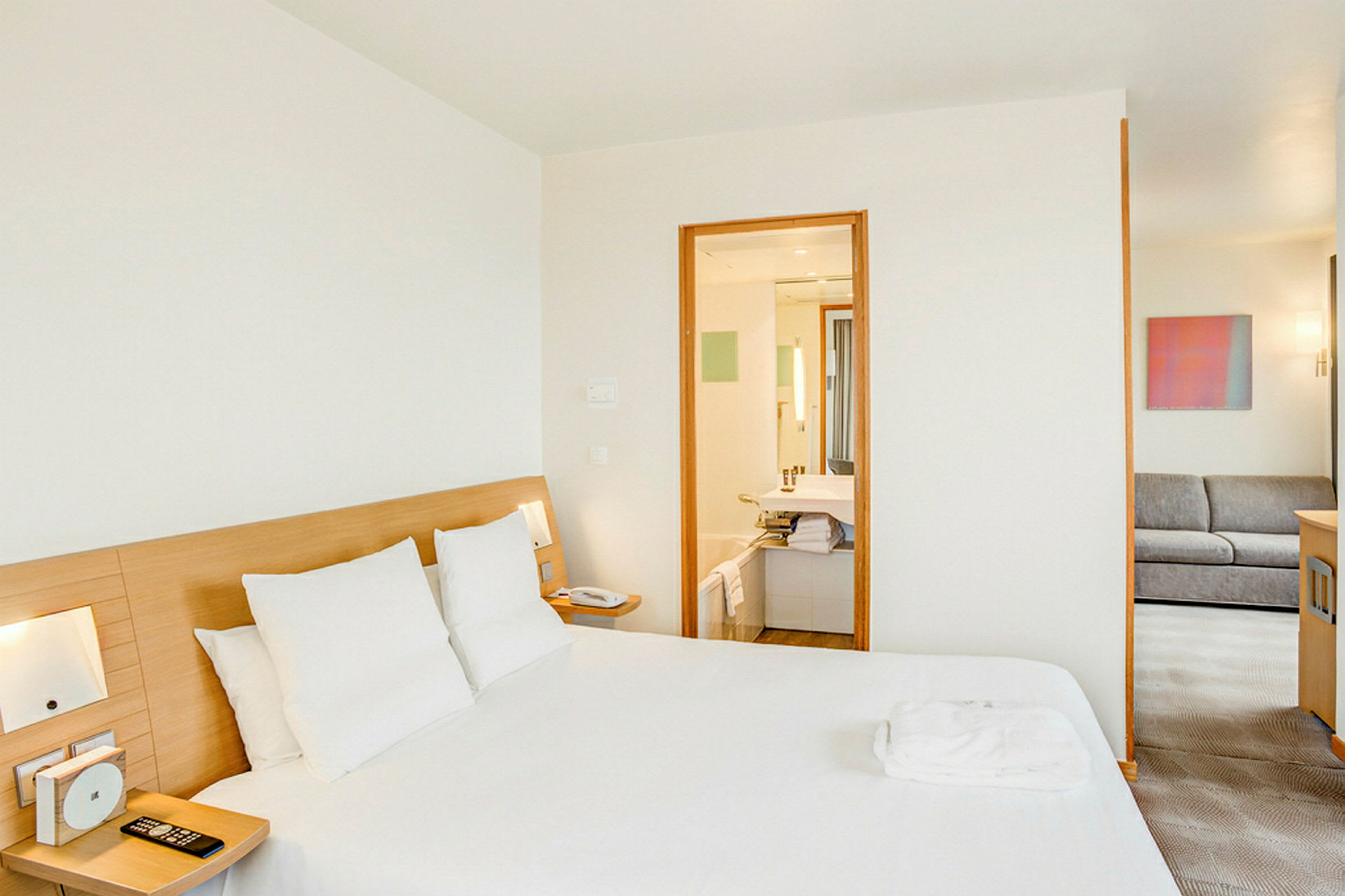 Ett hotellrum med en dubbelsäng, badrum och en sittgrupp. (AI-genererad text)