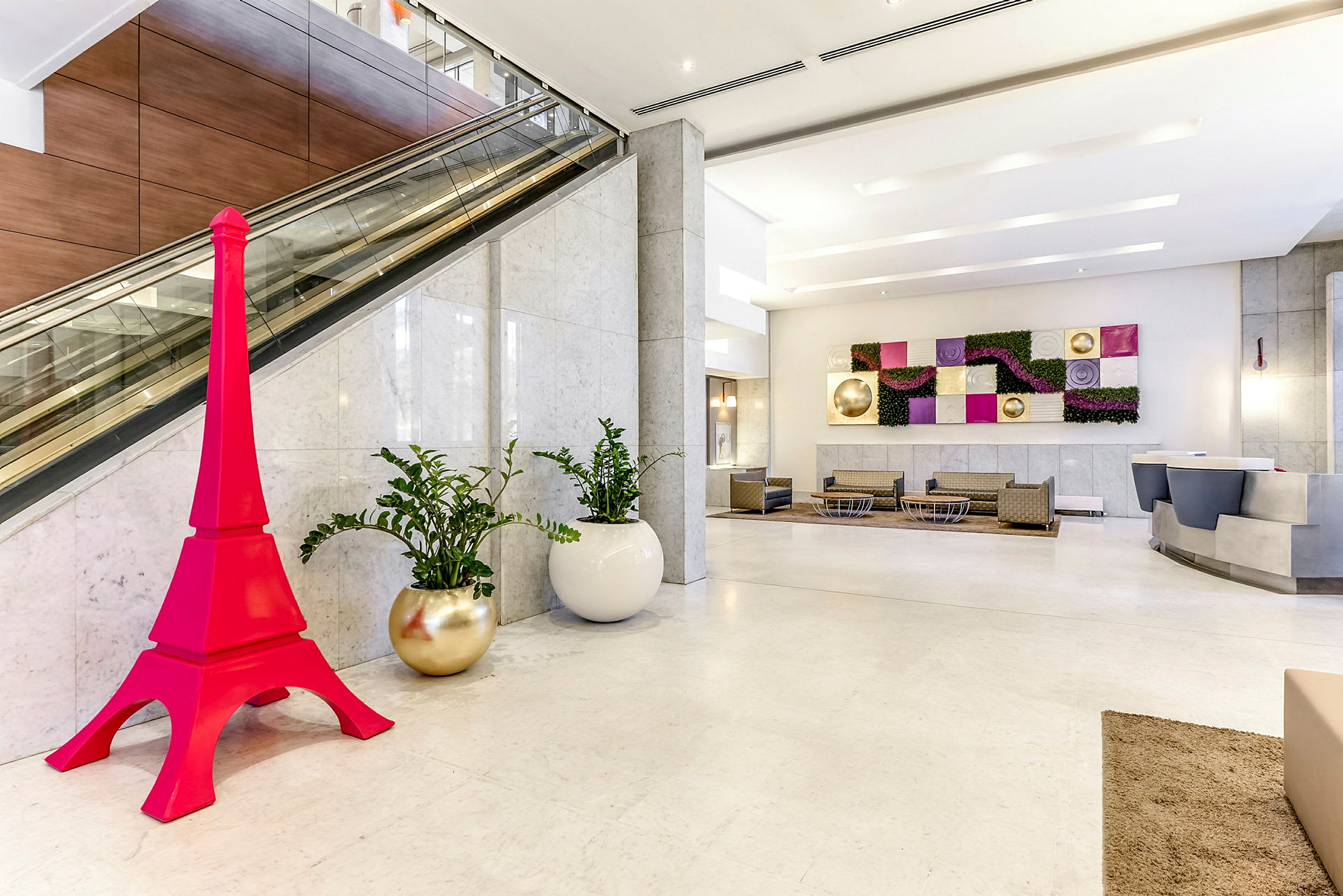Hotellobby med modern inredning, inklusive en rosa prydnad i form av ett torn. (AI-genererad text)