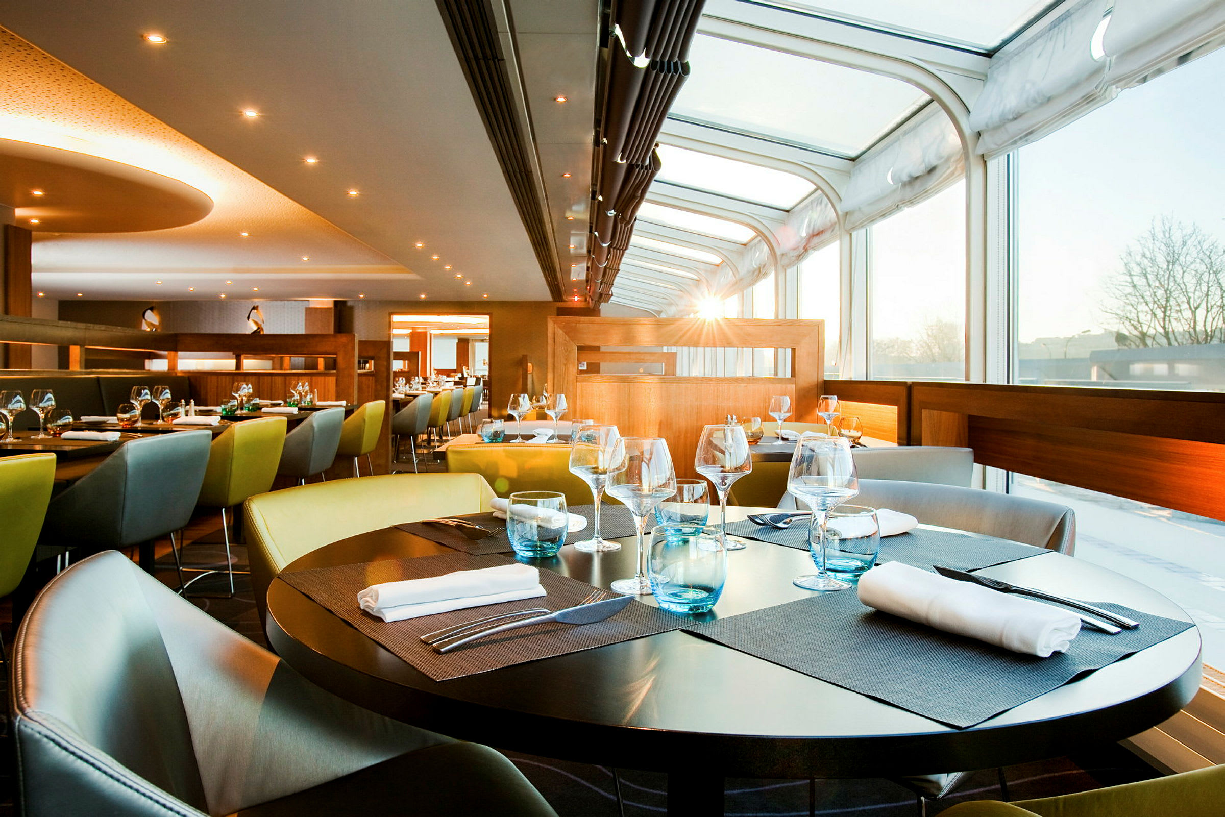 En modern restaurang med glasväggar och uppdukade bord med servetter och glas. (AI-genererad text)
