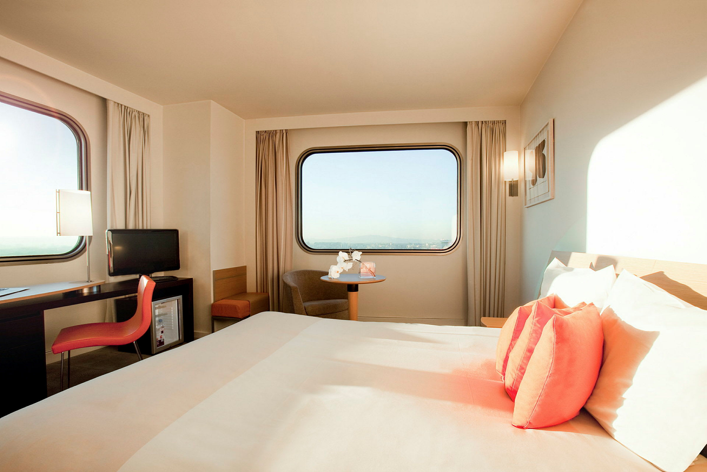 Ett hotellrum med en säng och en skrivbordsmöbel, två fönster med utsikt. (AI-genererad text)