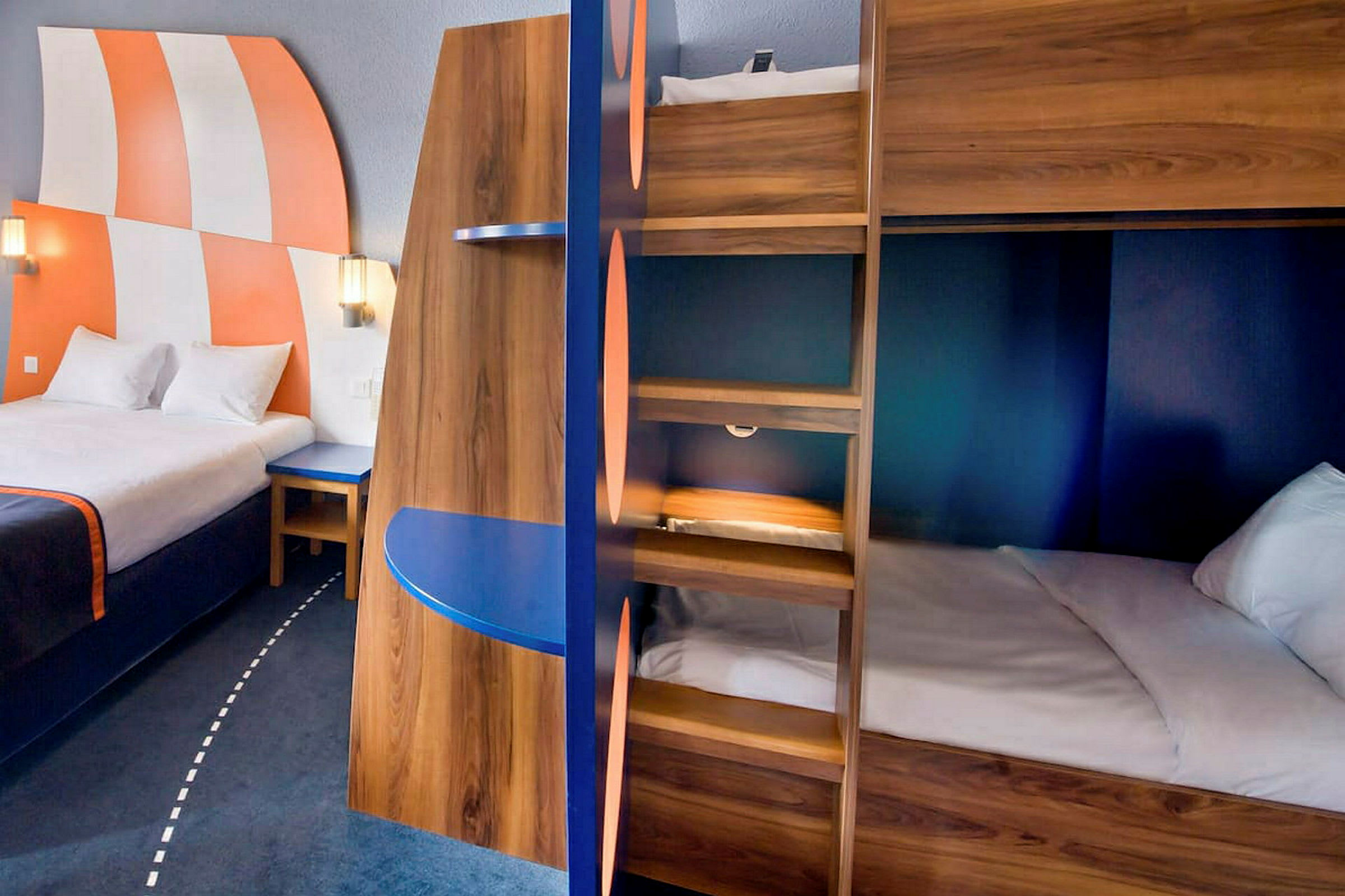 Interiör av ett hotellrum med en stor säng, våningssängar och färgglada detaljer. (AI-genererad text)