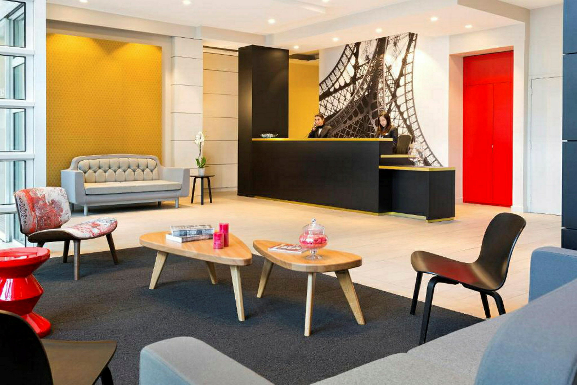 Ett modernt hotellreceptionsområde med ljus inredning, sittgrupp och en receptionsdisk. (AI-genererad text)