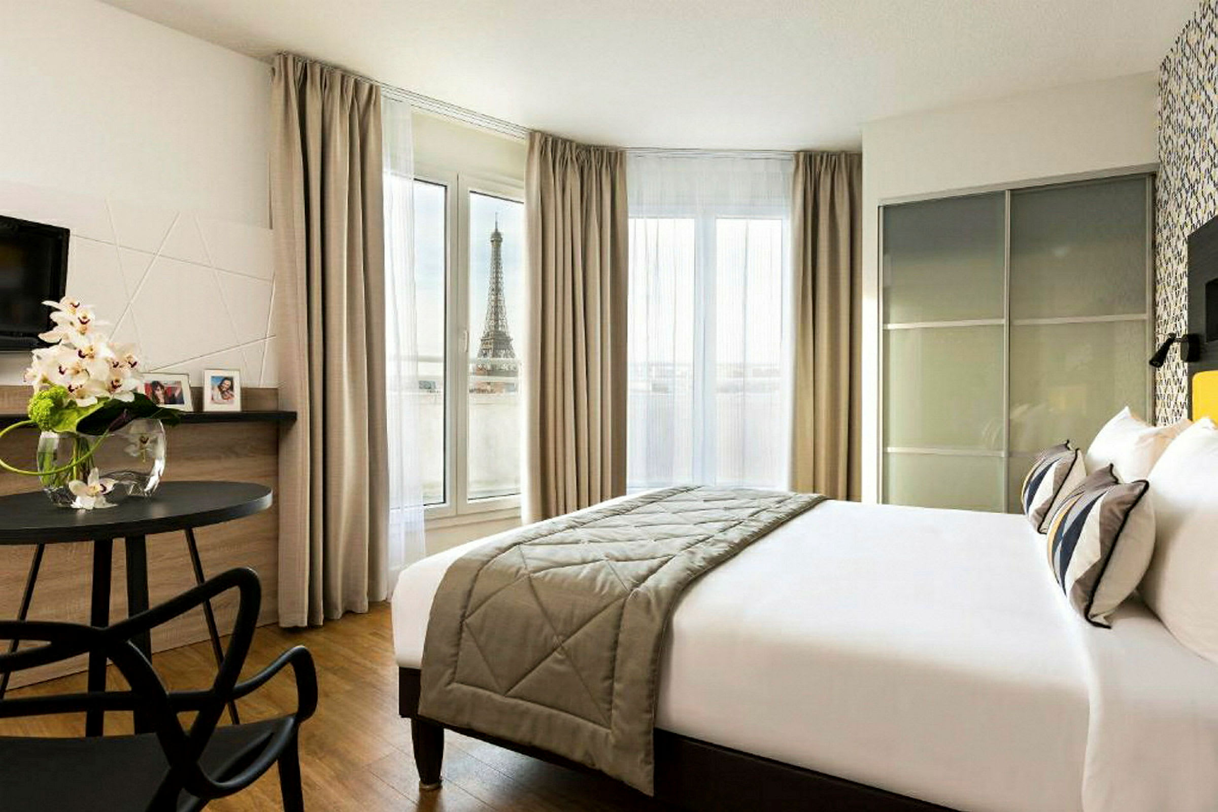 Ett hotellrum med utsikt över Eiffeltornet från ett fönster. (AI-genererad text)