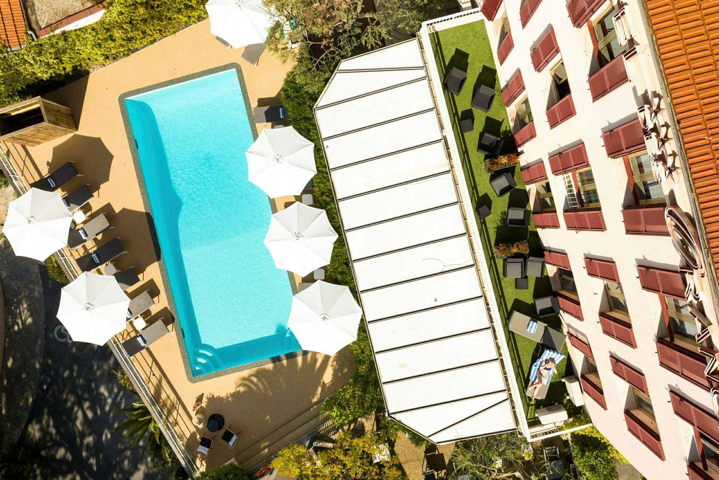 Bild av en pool, solstolar och parasoller vid sidan av en byggnad. (AI-genererad text)
