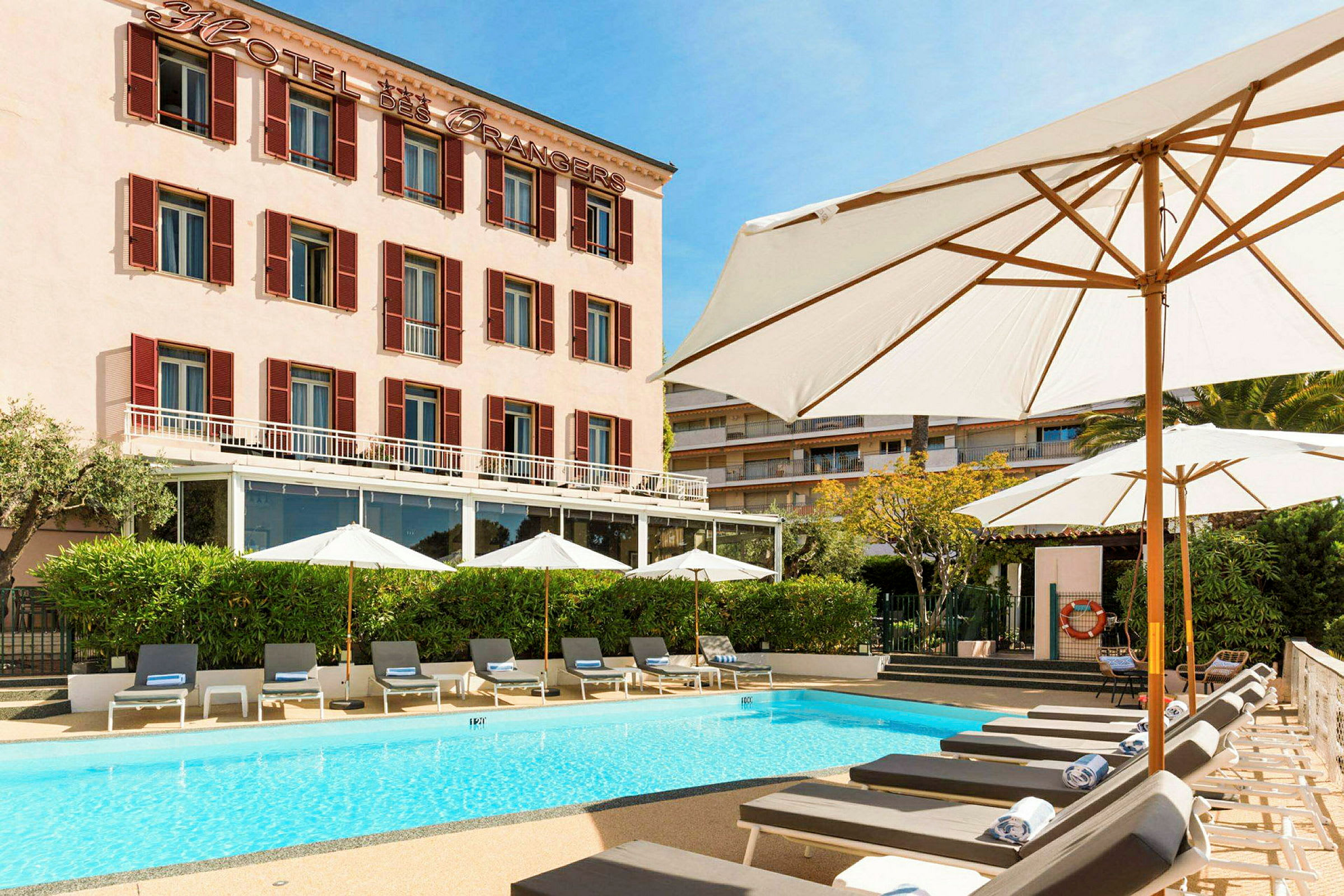 Hotellbyggnad med pool och solstolar framför. (AI-genererad text)