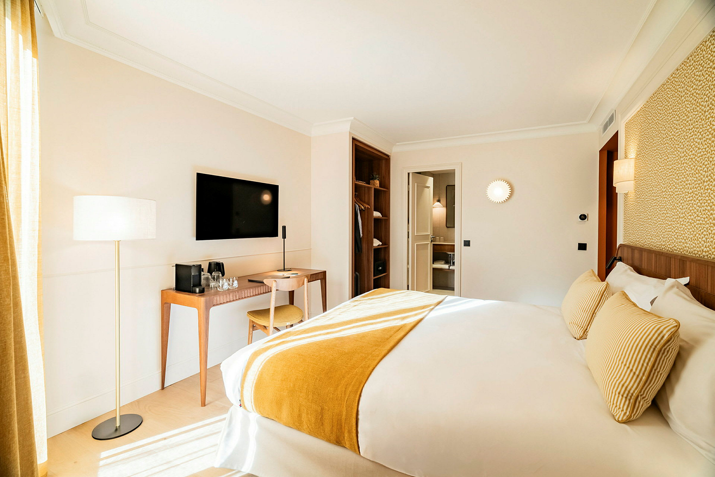 Ett hotellrum med en stor säng, skrivbord och stol samt en väggmonterad TV. Rummet är ljust inrett. (AI-genererad text)
