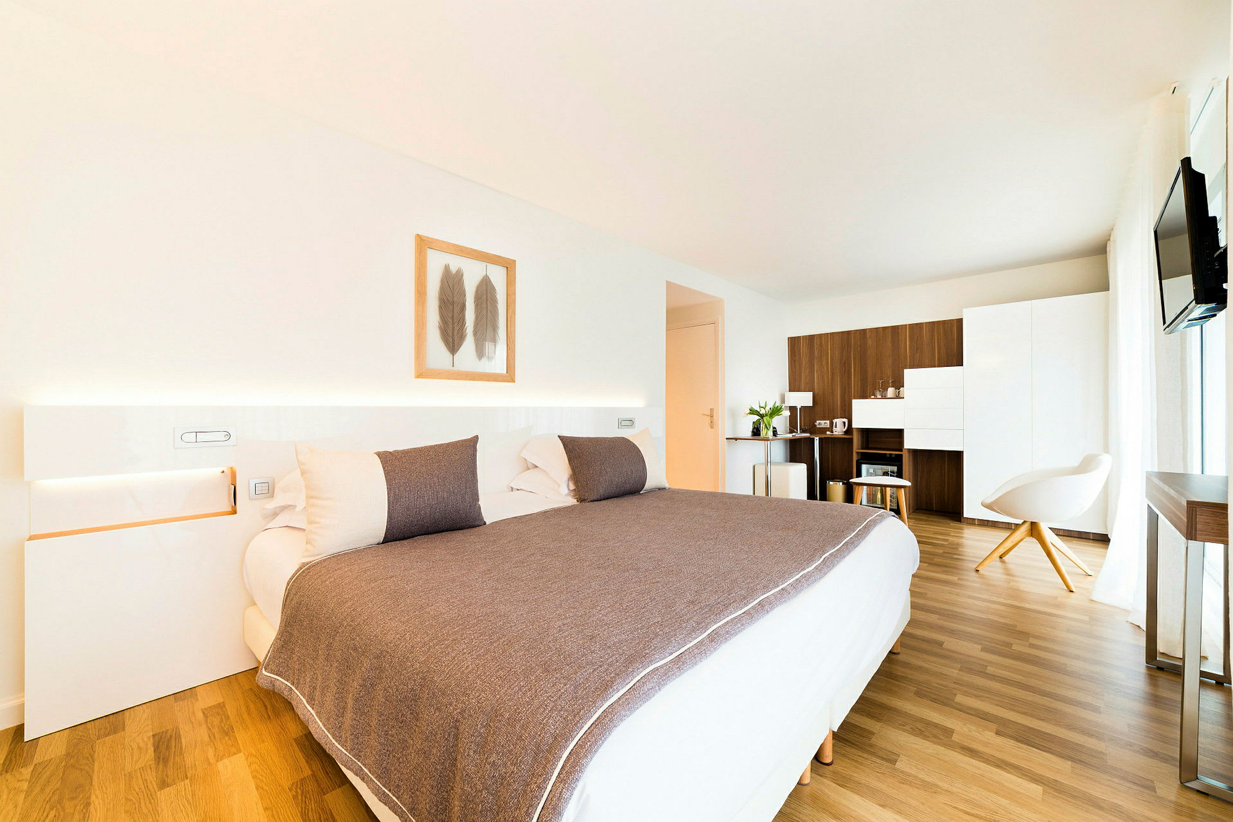Ett modernt hotellrum med en stor säng, minimalistisk inredning och trämöblemang. (AI-genererad text)