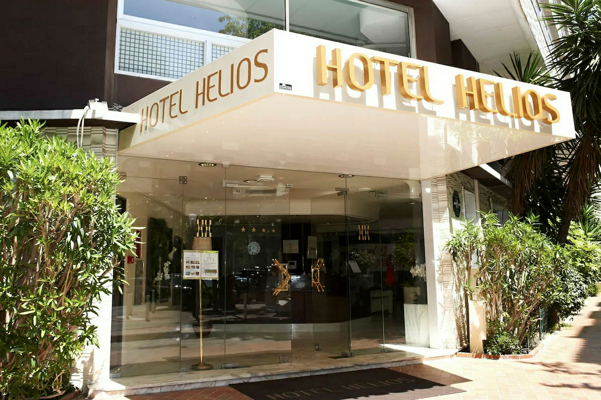 Entrén till hotellet Hotel Helios med namnet skrivet ovanför entrén. (AI-genererad text)