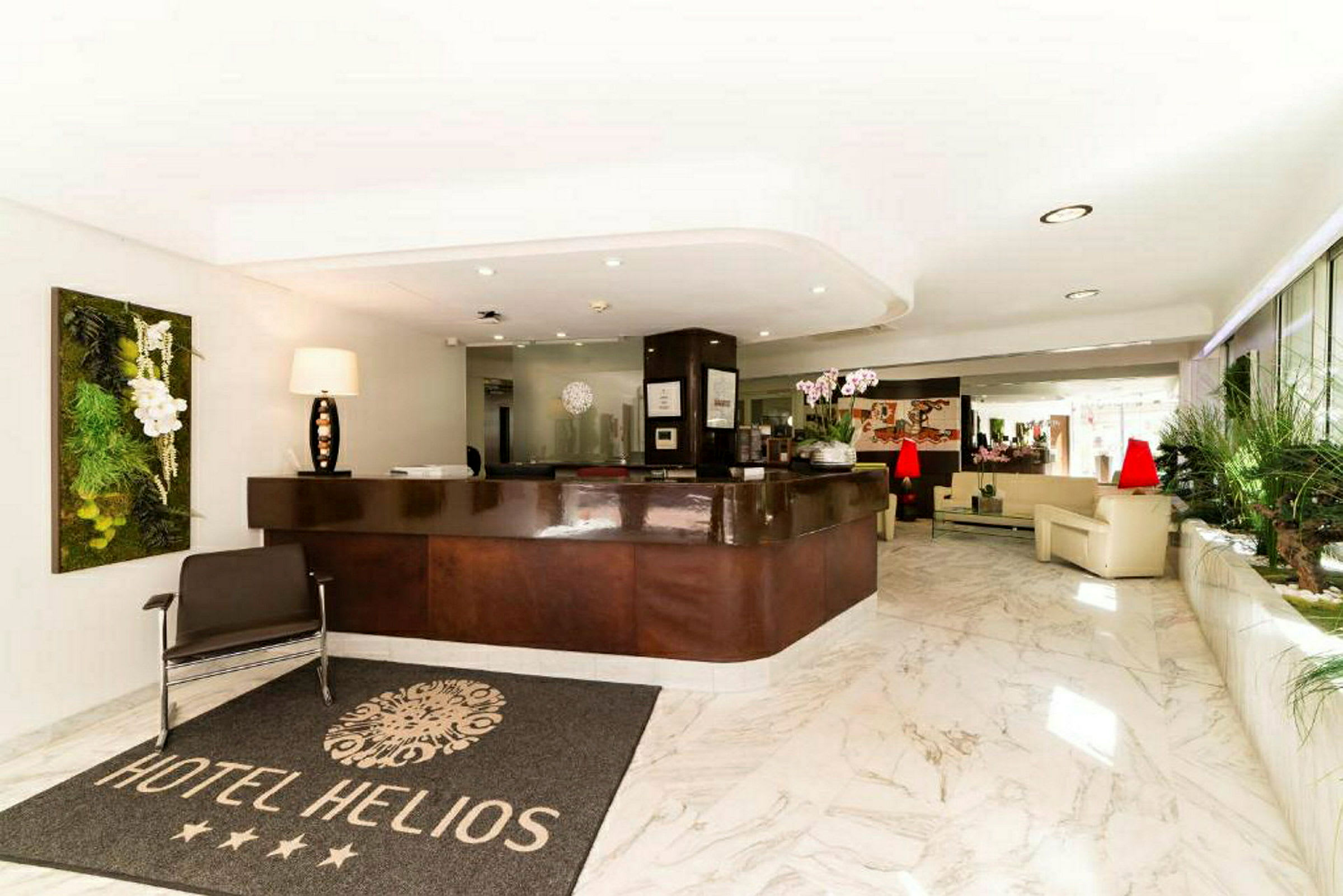 Hotellobby med reception, en matta med texten "Hotel Helios" och sittmöbler i ljus miljö. (AI-genererad text)