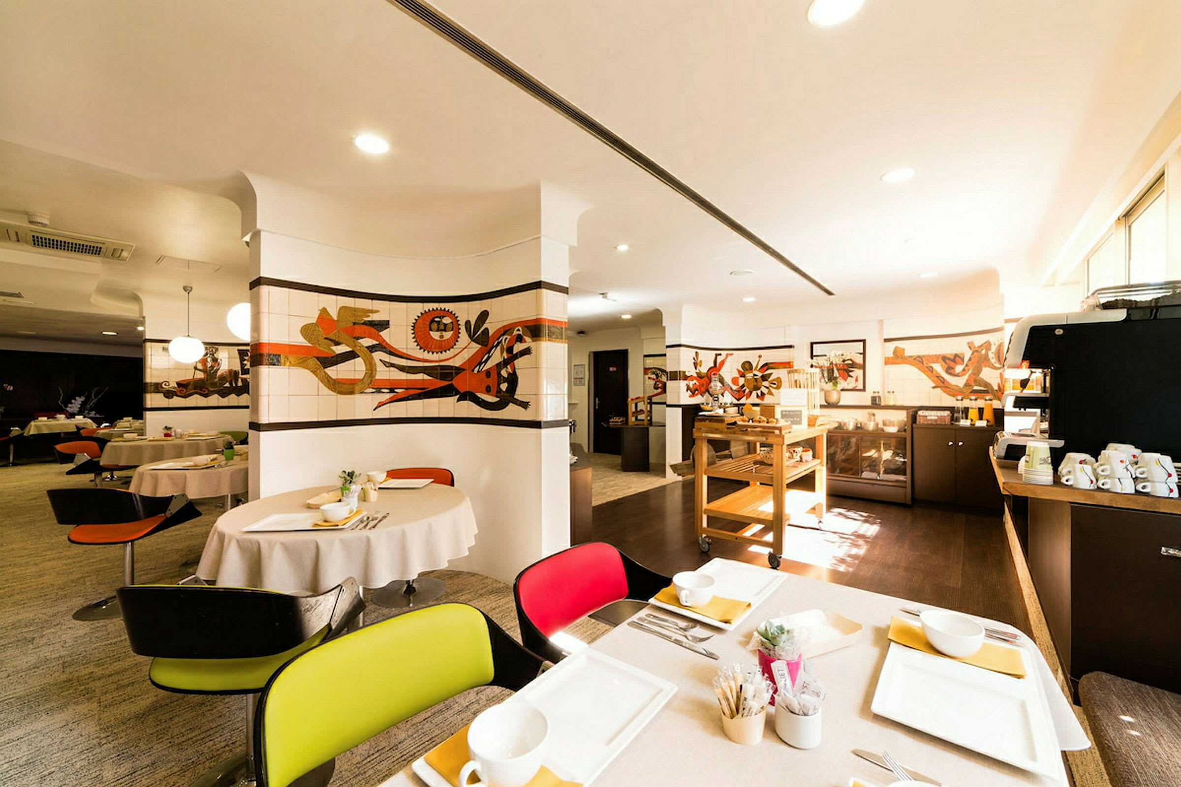 En restaurang med dukade bord, konst på väggarna och en serveringsstation. Ljuset är varmt och välkomnande. (AI-genererad text)