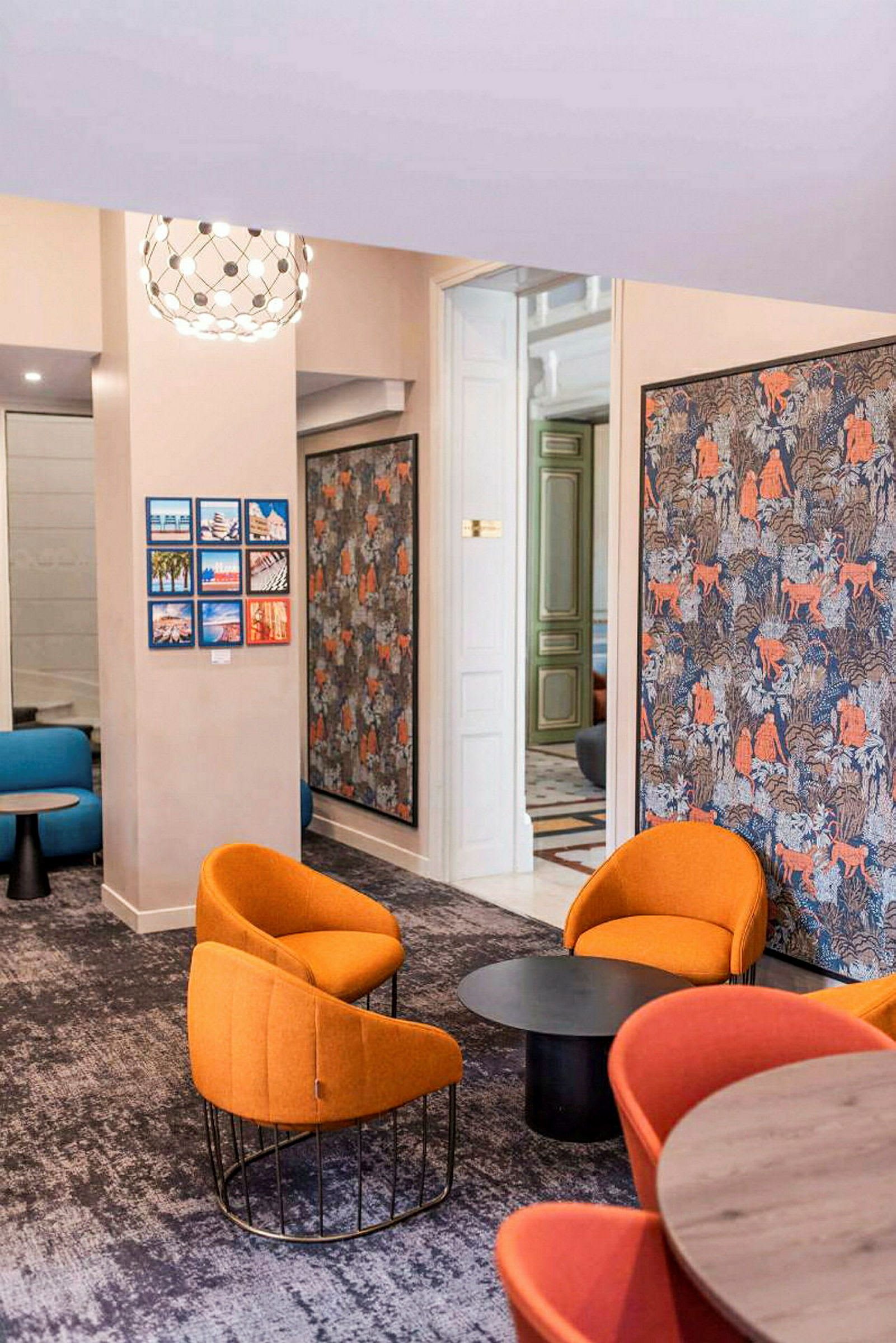 Ett modernt inrett rum med flera sittplatser, orange och blå fåtöljer samt dekorativa väggpaneler. (AI-genererad text)